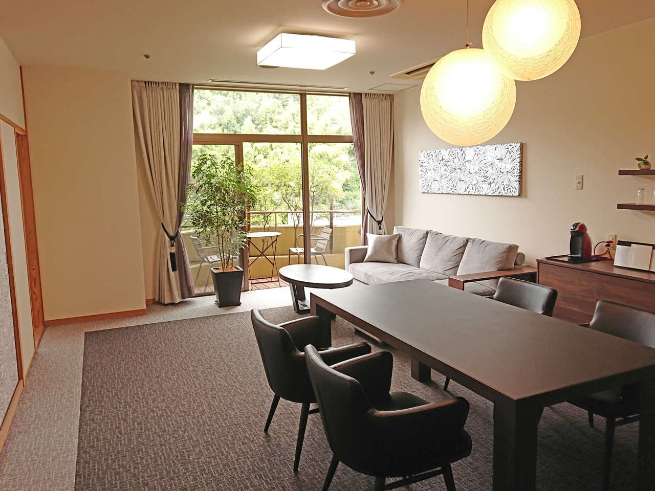 Premium suite living room with sofa, dining table and balcony overlooking greenery at Dogo Onsen Hanayuzuki