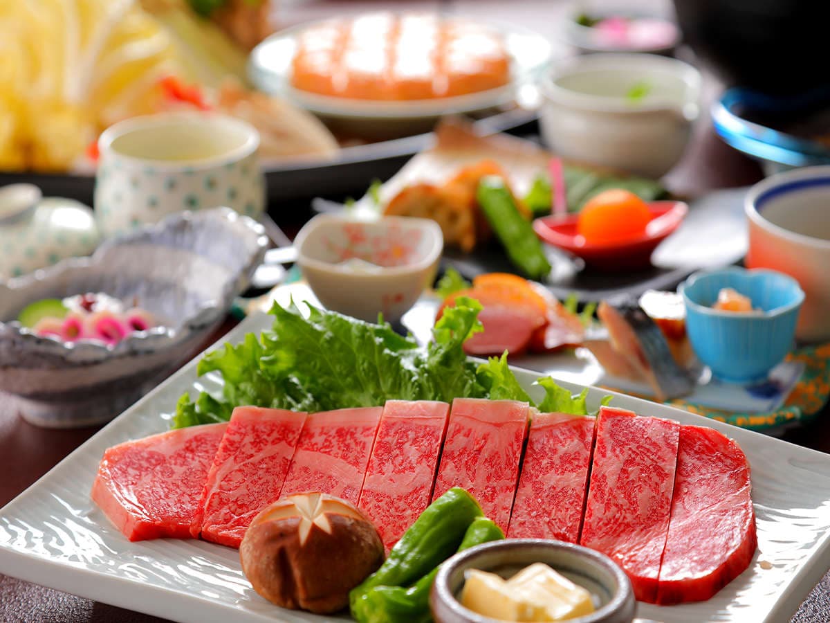 Course dinner spread featuring marbled wagyu beef plated with vegetables and small side dishes at Sanseikan