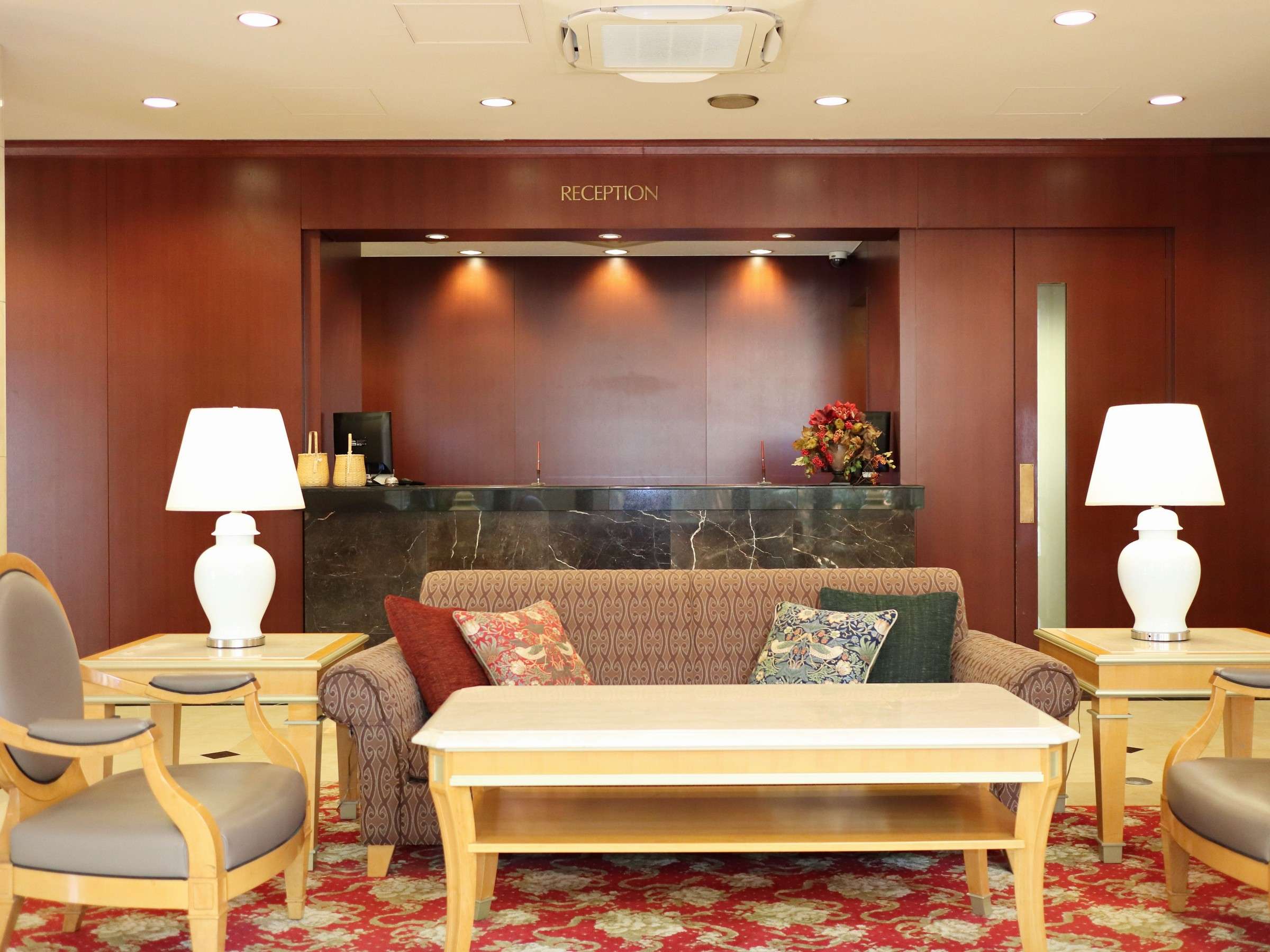Reception lounge at Hotel Patio Dogo with sofa, table lamps and patterned carpet