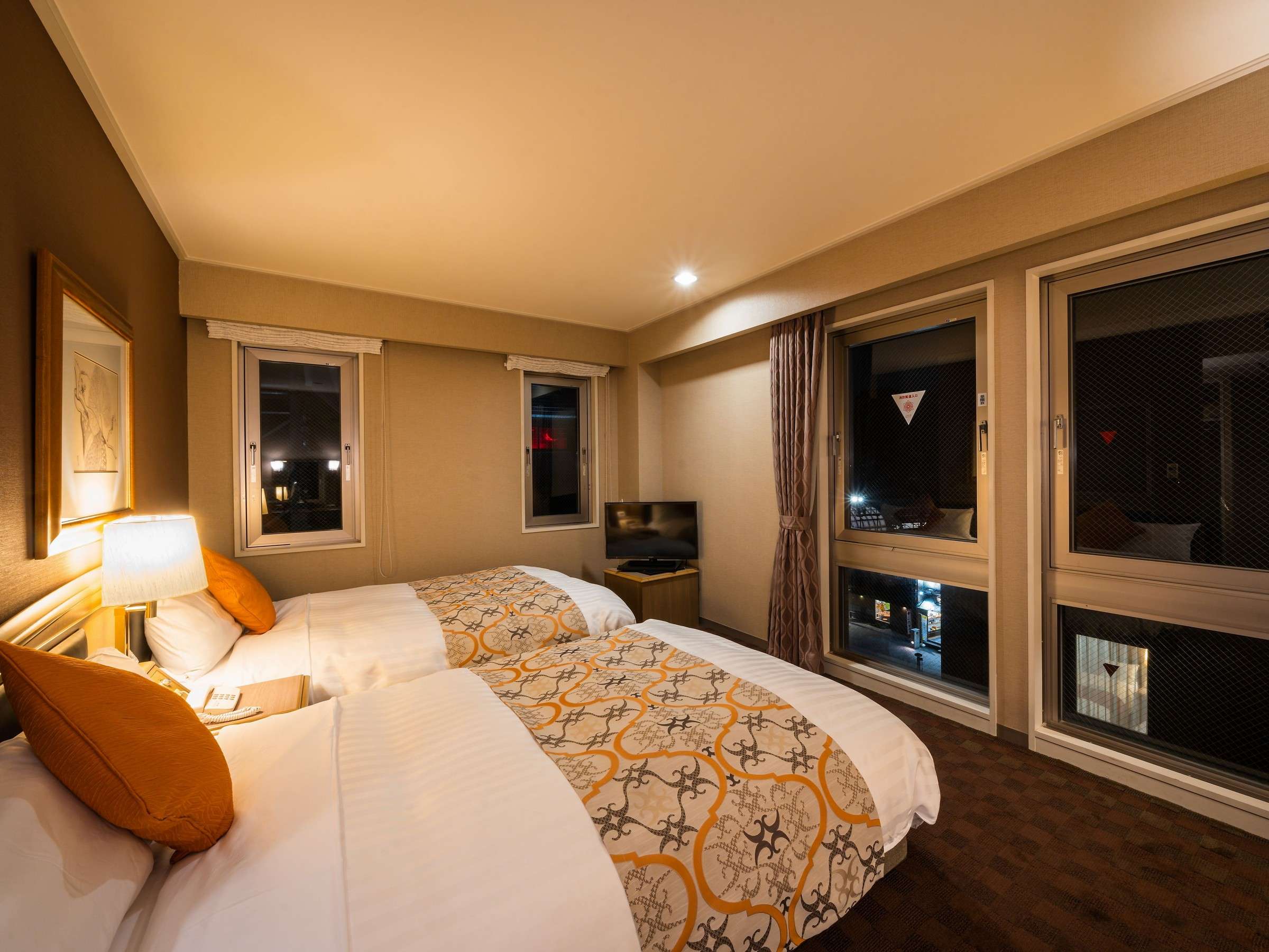 Twin guest room at night with town view through the windows at Hotel Patio Dogo