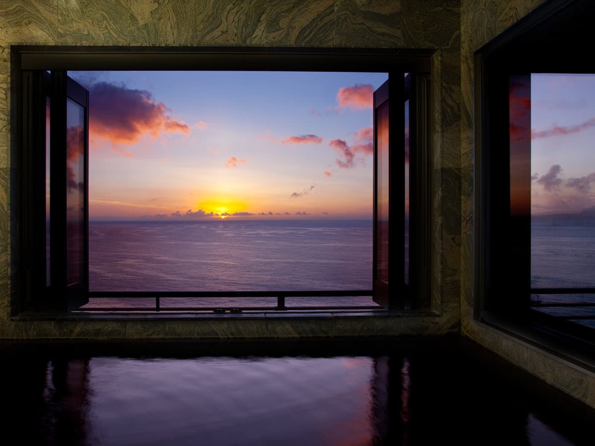 In-room stone bath at Kissho Caren overlooking a vivid ocean sunset over the Izu sea