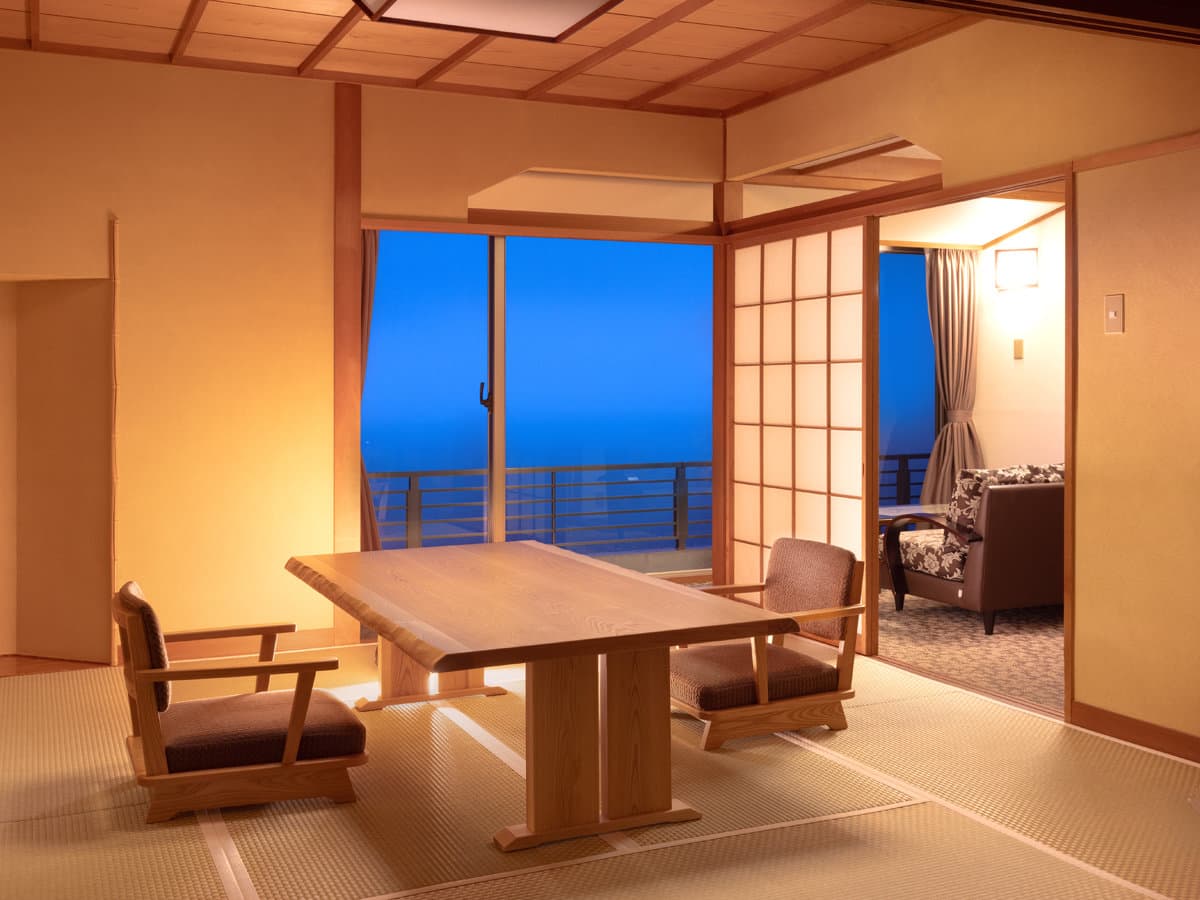 Japanese-style guest room with low table and sea view at dusk at Kissho Caren