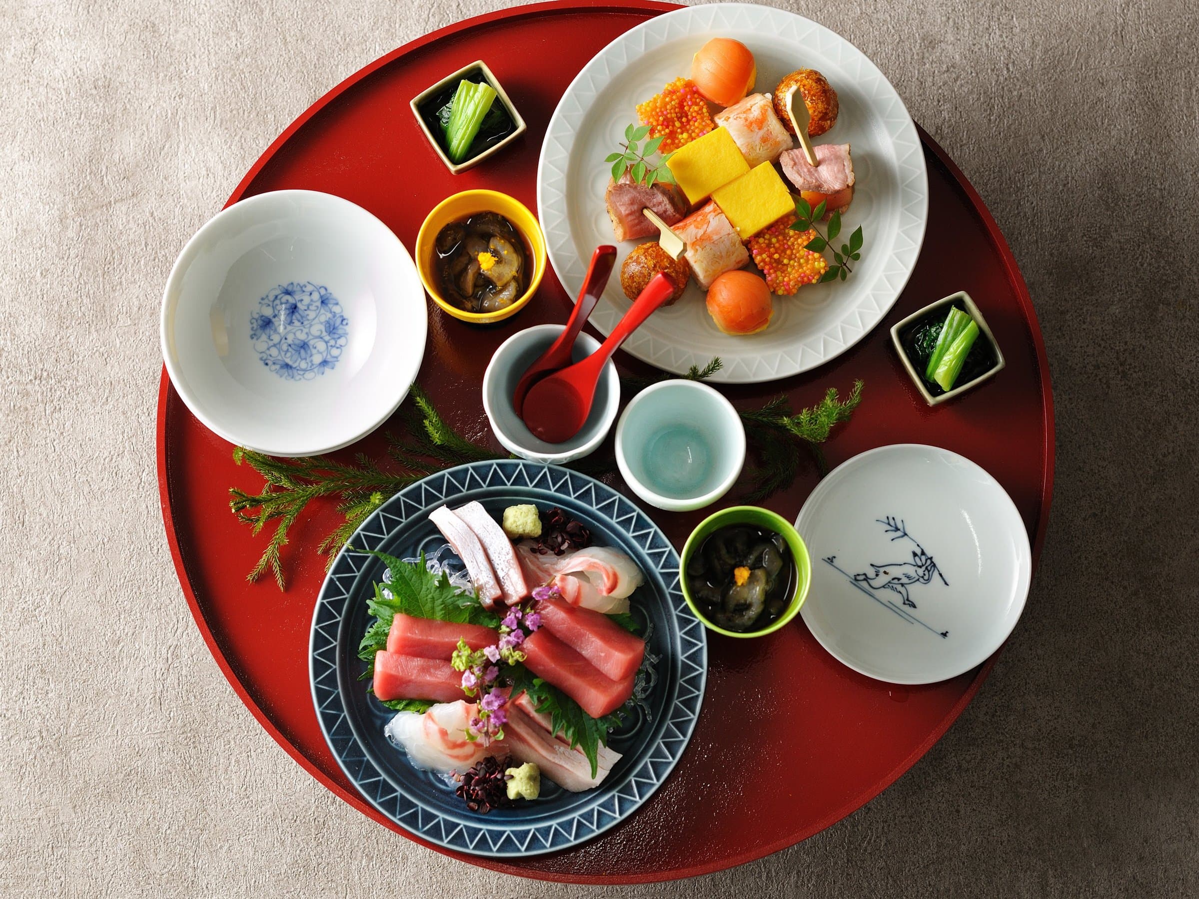Kaiseki appetizer course at KAI Unzen on a red lacquer tray with sashimi, rolled omelet and seasonal small dishes