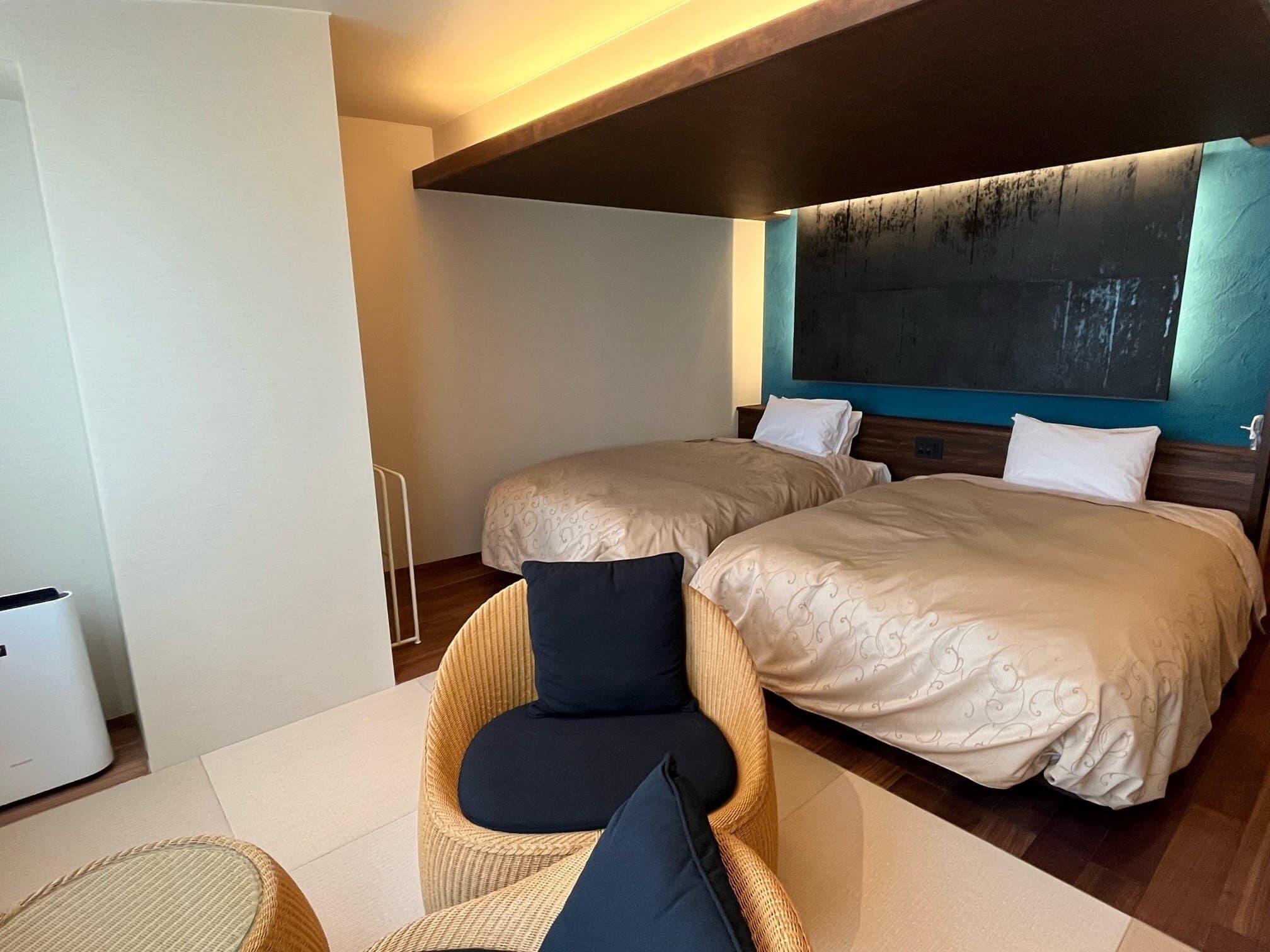 Modern twin guest room at Yuyado Miyuki Honkan with low beds, a teal feature wall and rattan armchairs on tatami