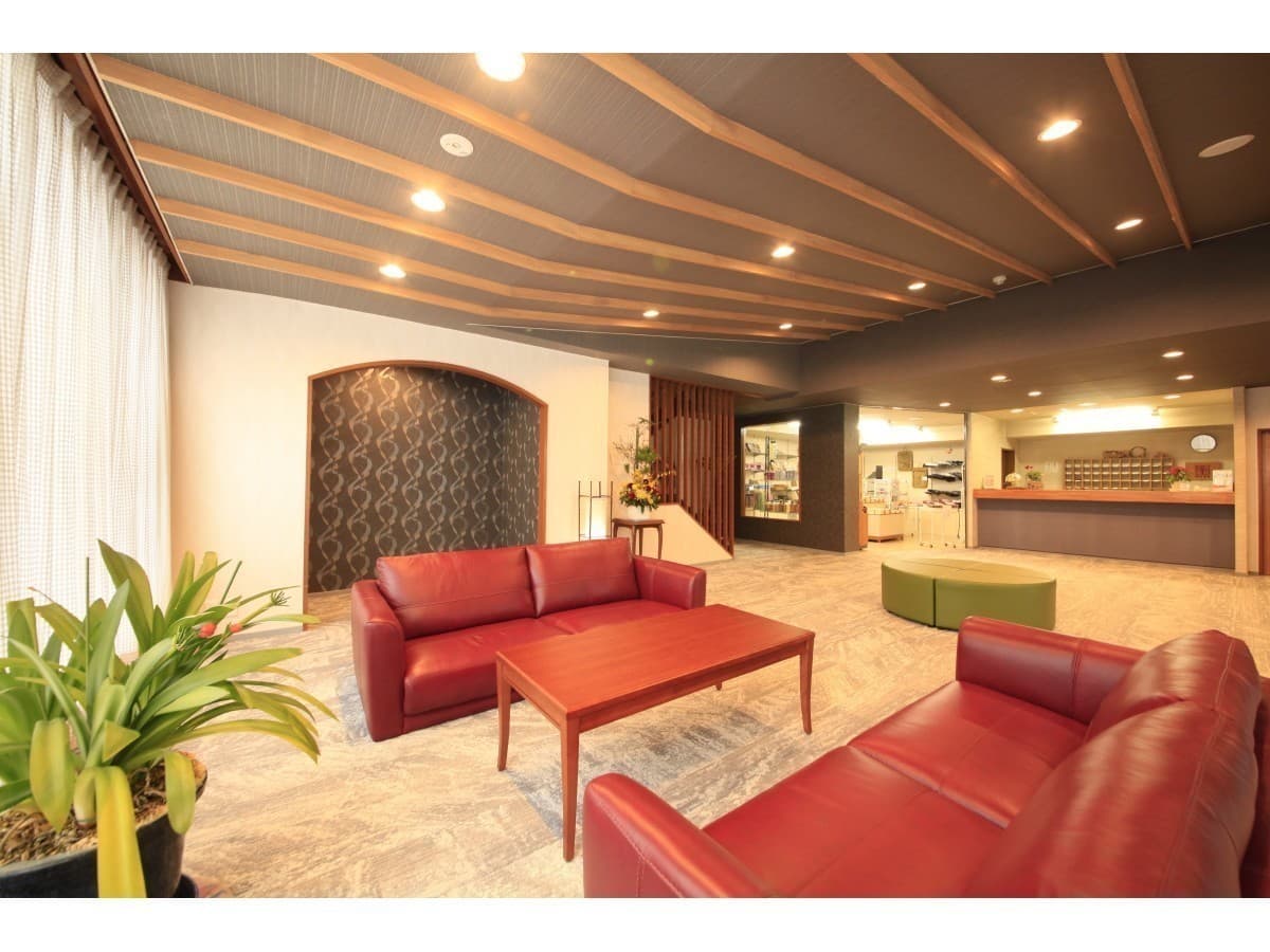 Lobby of Yuyado Miyuki Honkan with red leather sofas, a wood-slat ceiling and the front desk in the background