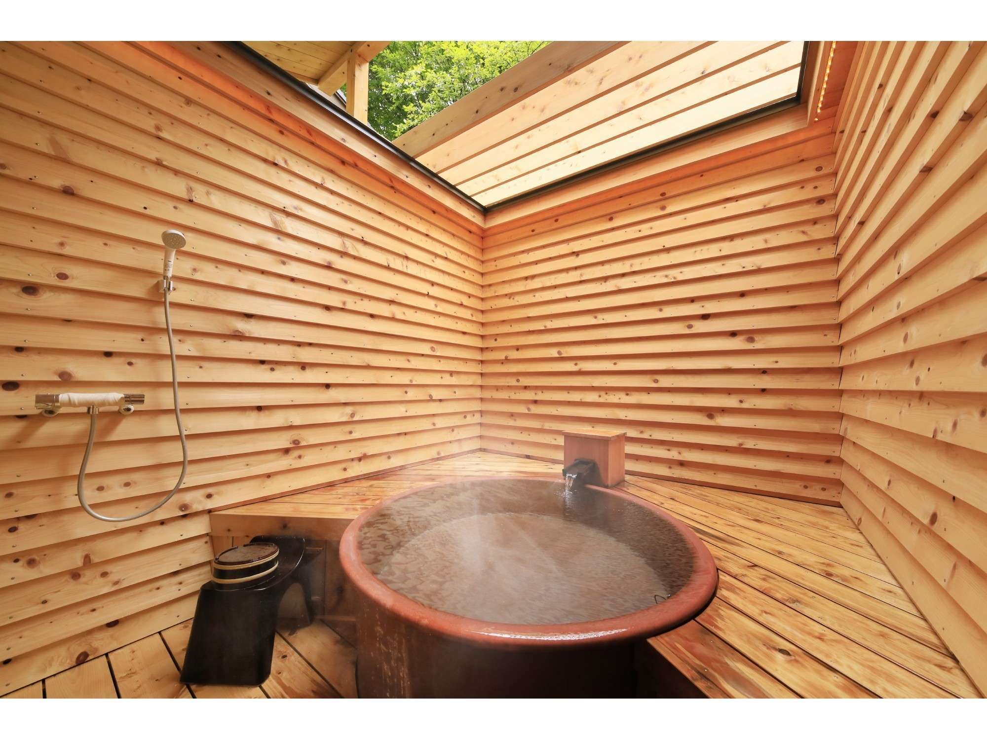 Private rental bath at Yuyado Miyuki Honkan with a round earthen tub in a fully cedar-clad room lit by a skylight