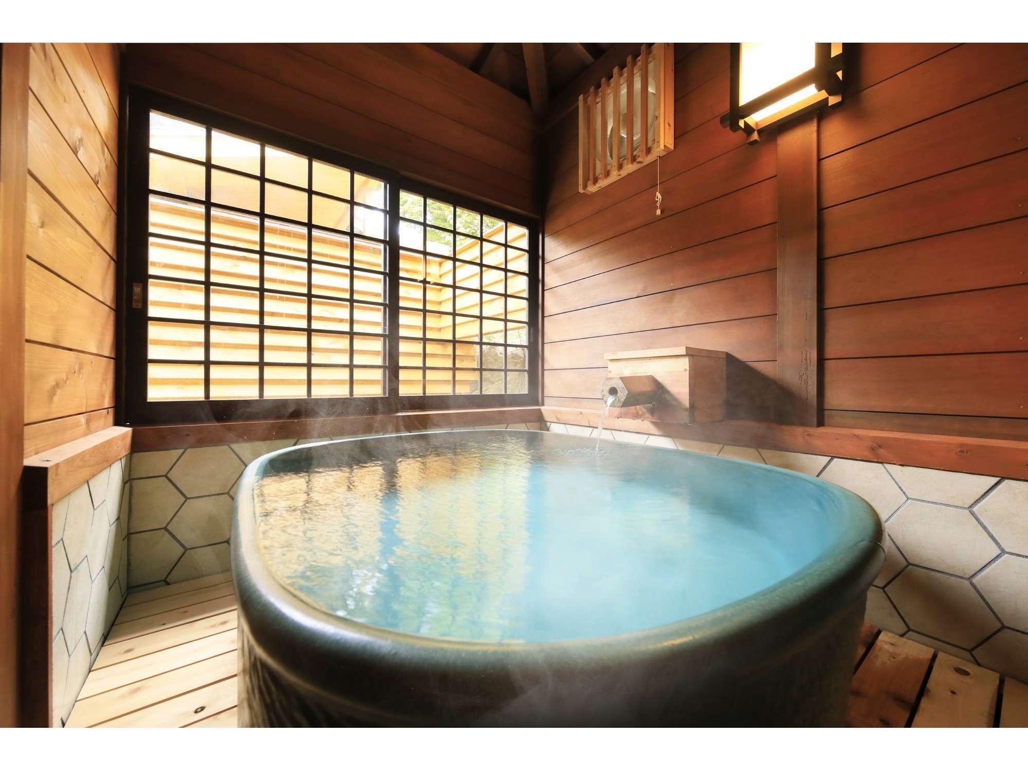 Private rental bath at Yuyado Miyuki Honkan with a glazed tub of steaming Kusatsu spring water beside a wood-framed window