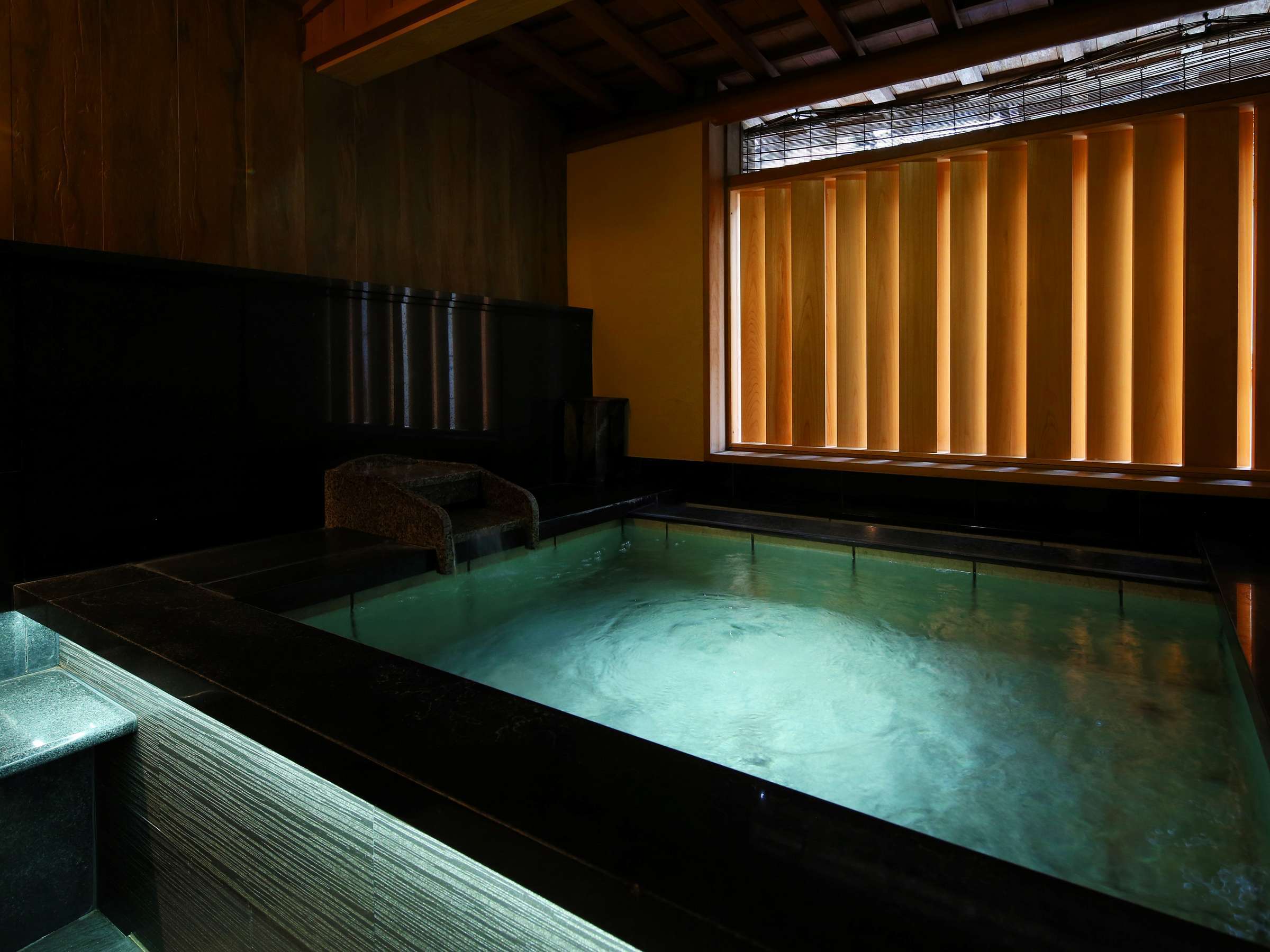 Dark stone indoor onsen bath at Ichidaya with mood lighting