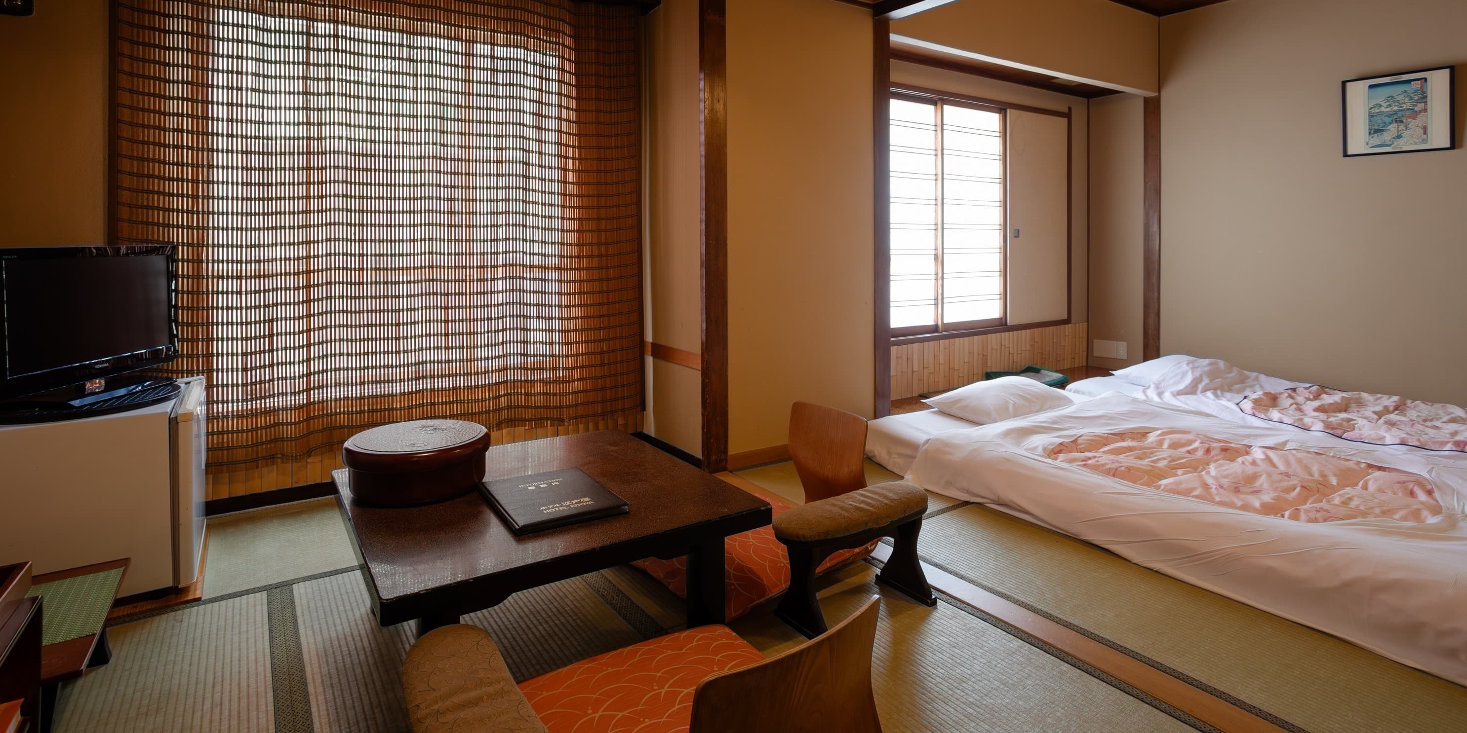 Tatami guest room with low wooden table, floor seating and bamboo blinds at Hotel Edoya in Yushima, Tokyo