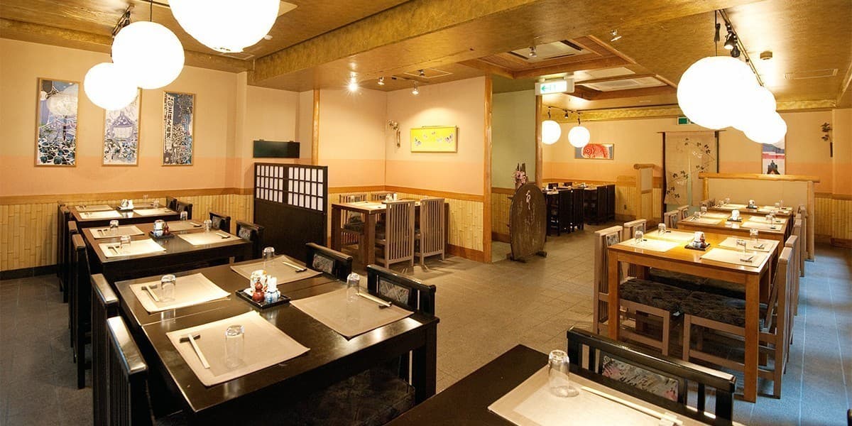 Japanese restaurant dining room with wooden tables, paper lanterns and woodblock prints at Hotel Edoya, Tokyo