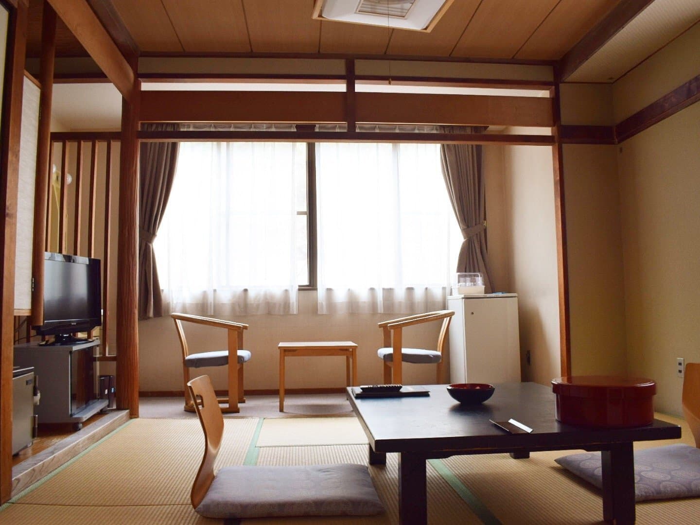 Bright Japanese-style tatami room at Soraichi with large window, wooden chairs and low dining table
