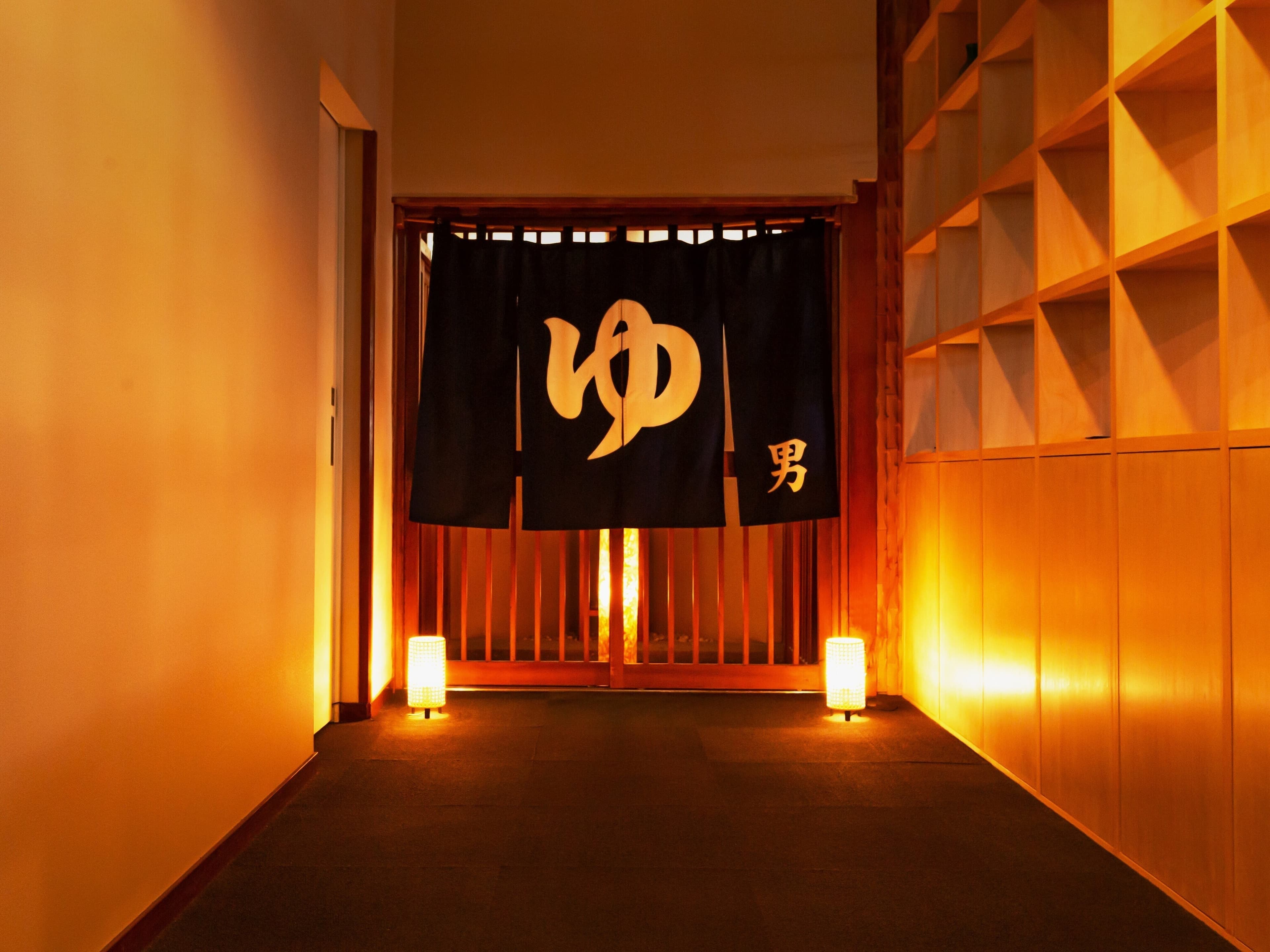 Lantern-lit corridor to the men's bath at Soraichi with traditional noren curtain