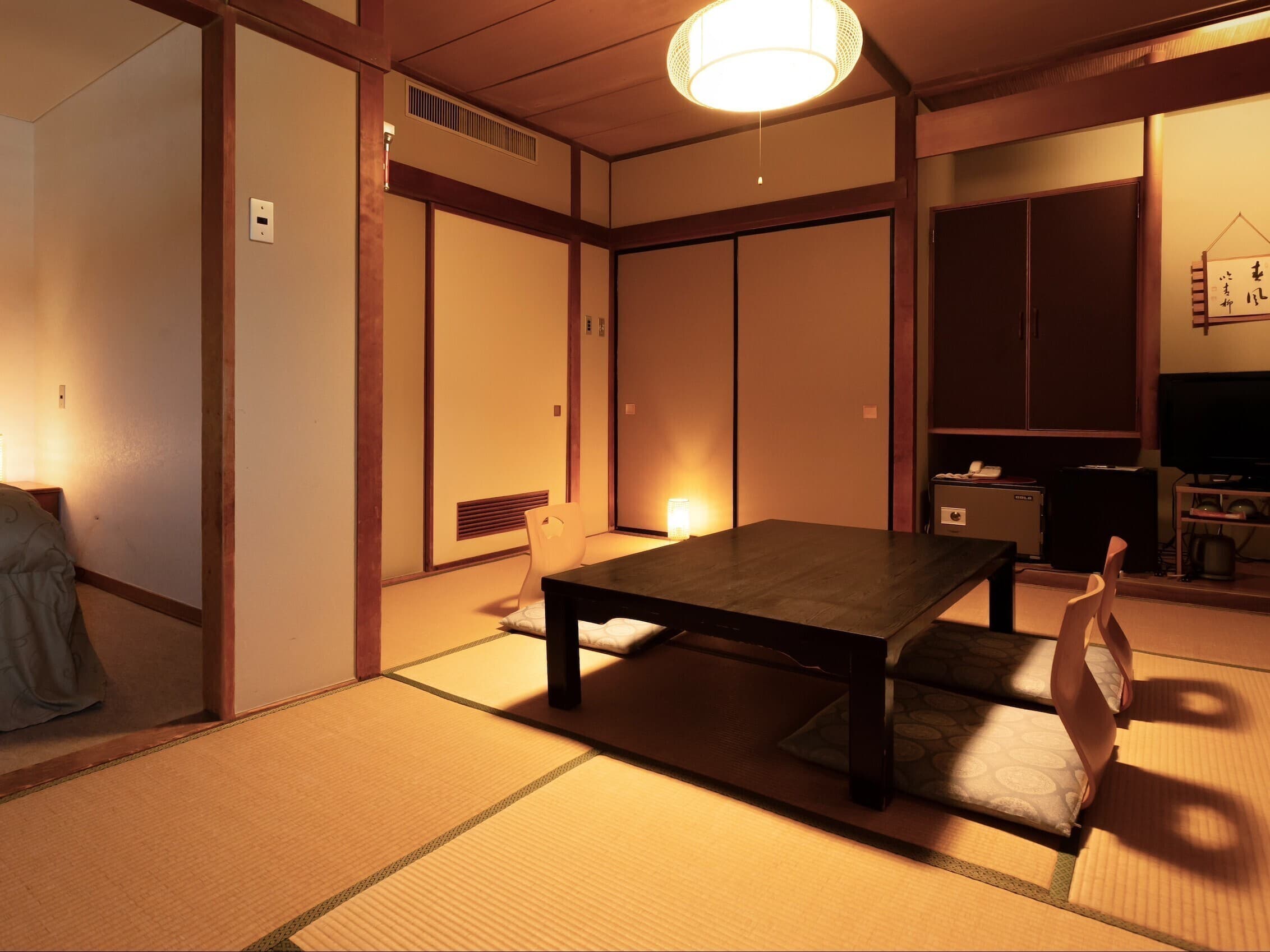 Spacious tatami guest room at Soraichi with low table, floor cushions and warm evening lighting