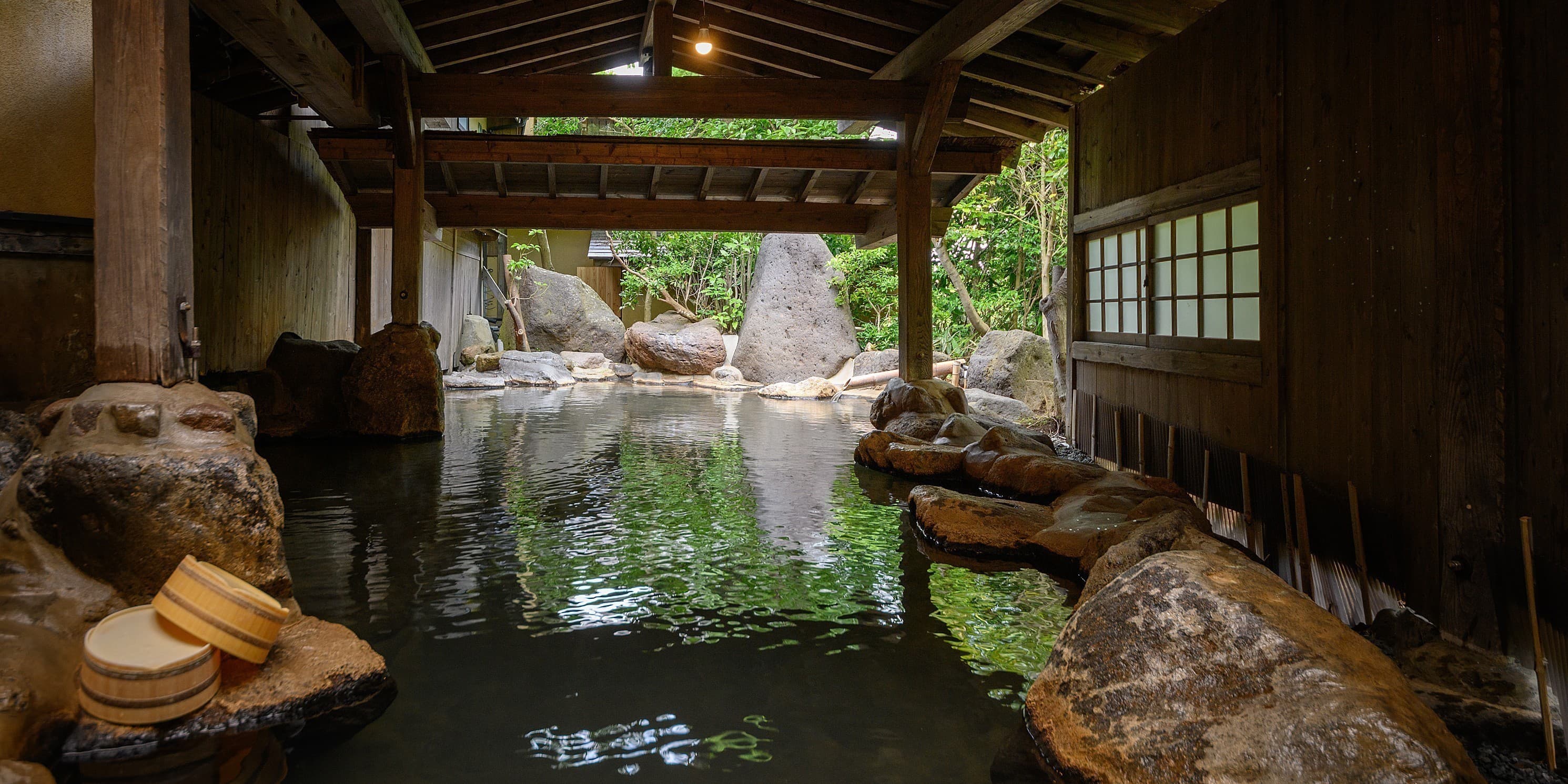 Yumerindo Tennyo-no-yu wood-framed open-air rotenburo with large boulders and bath buckets