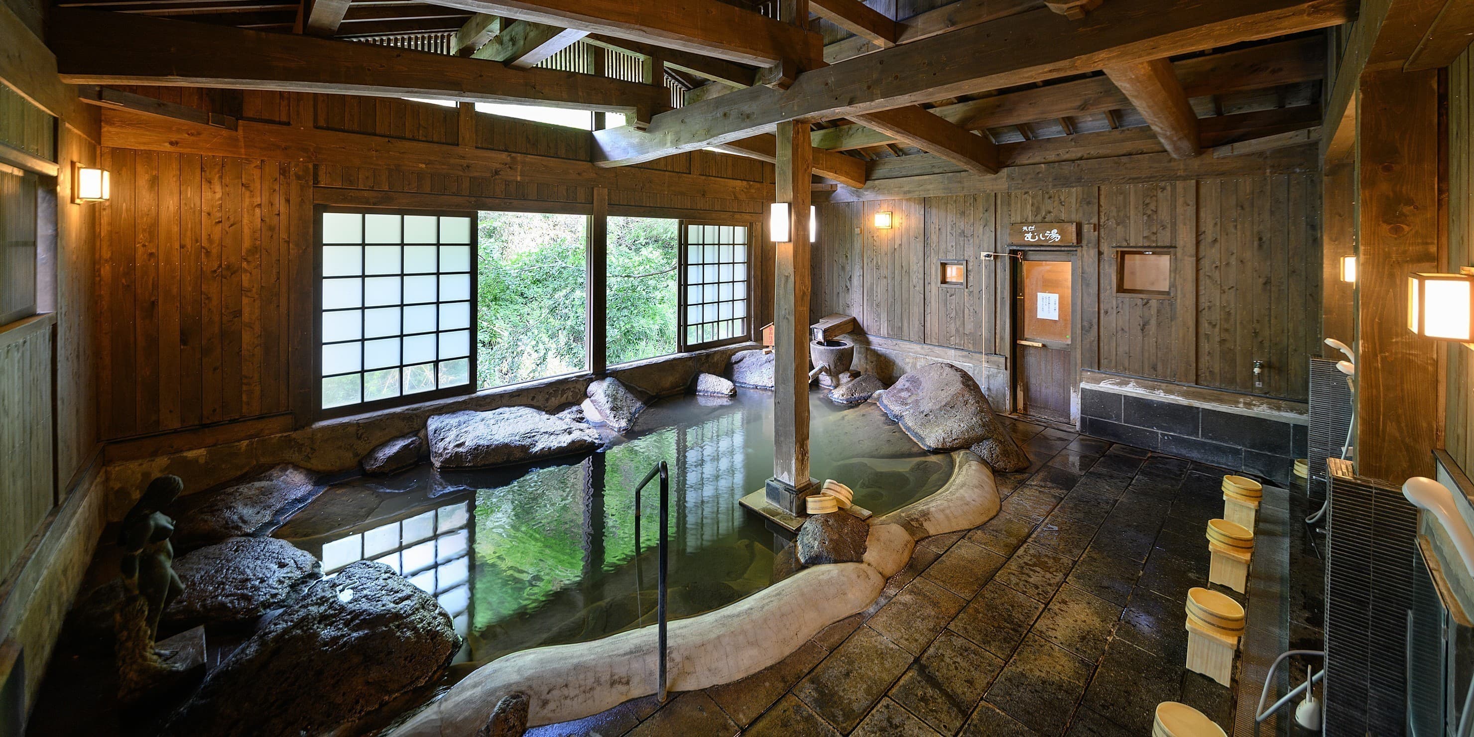 Yumerindo Seseragi-no-yu wooden indoor bath with timber beams, rocks and shoji windows