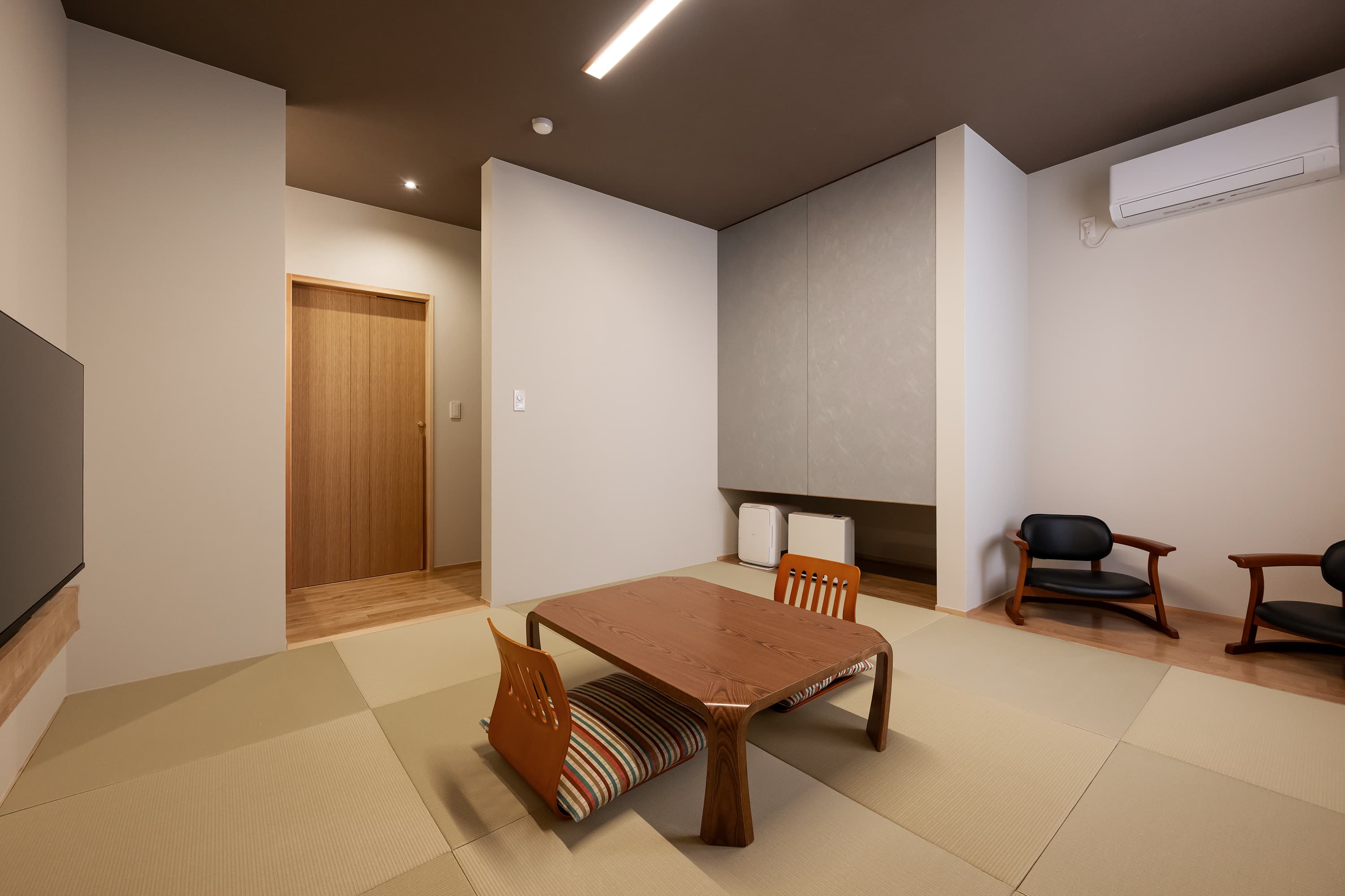 Western-Japanese hybrid guest room at Kusatsu Onsen Hoshikawa with tatami flooring, a low table and lounge chairs
