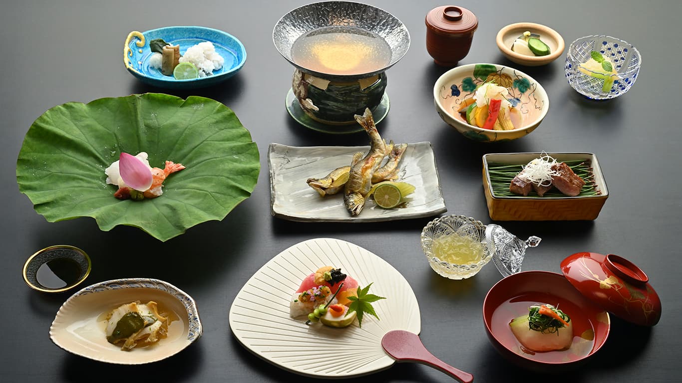 Kaiseki dinner courses presented on a lotus leaf and assorted ceramic dishes at Ginsuiso Choraku