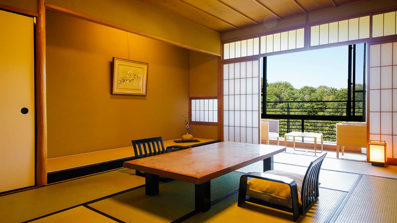 Tatami guest room with a low table and sweeping mountain view through the window at Ginsuiso Choraku