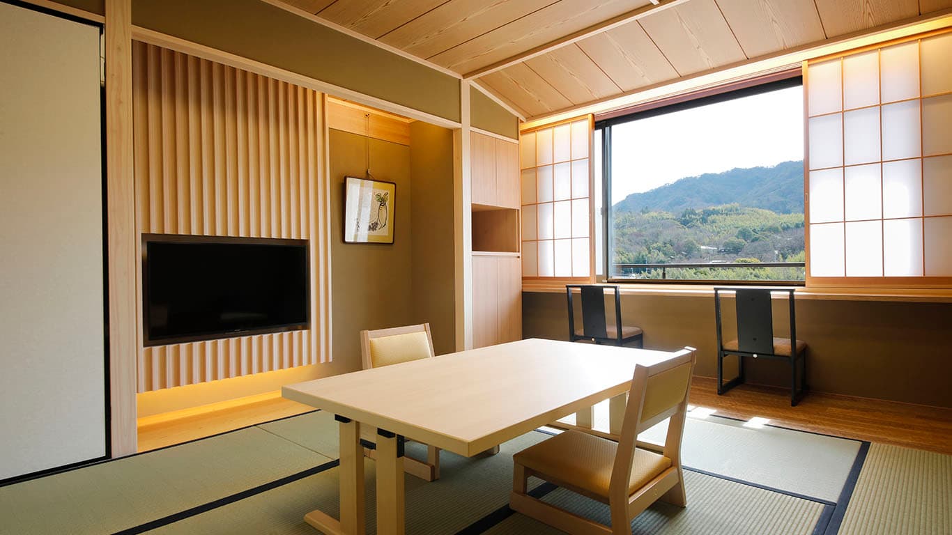 Premium tatami suite with a lounge sofa and large garden window at Ginsuiso Choraku