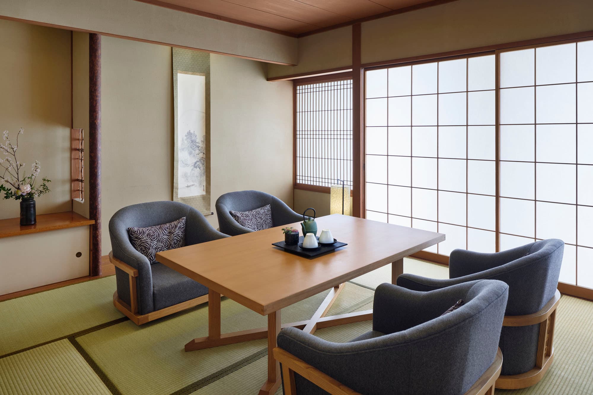 Japanese Deluxe Suite lounge with tatami, low table, grey armchairs and hanging scroll at Takanawa Hanakohro Tokyo