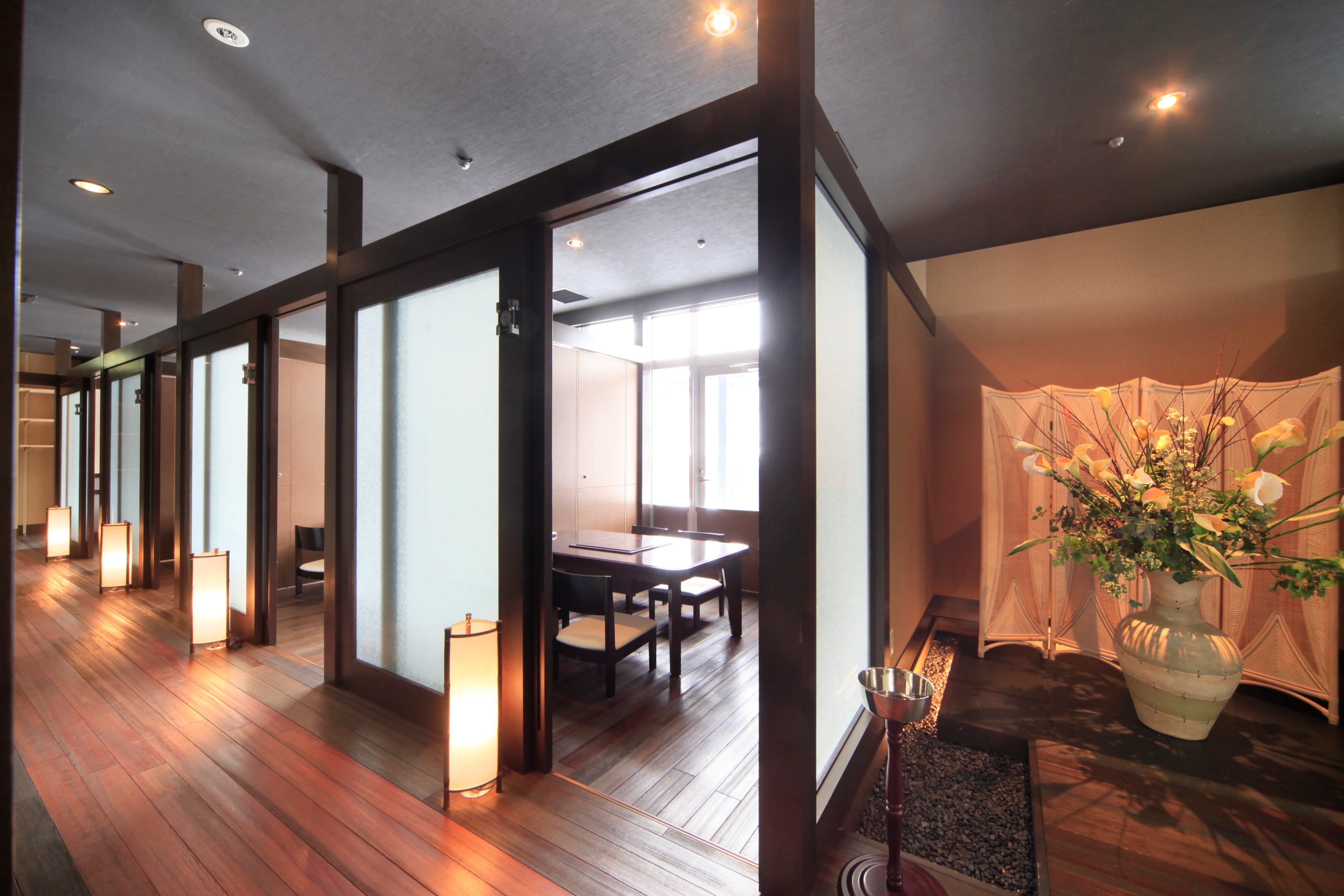 Dining corridor with paper lanterns, semi-private booths and a flower arrangement