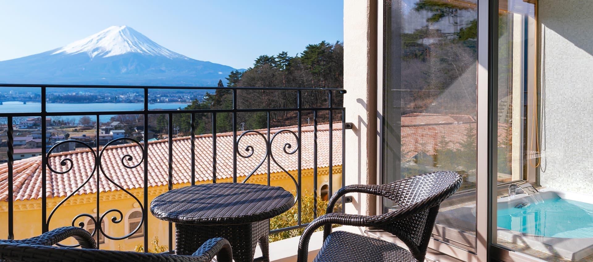 Private balcony at La Vista Fuji Kawaguchiko with wrought-iron table overlooking Mt Fuji and Lake Kawaguchiko, and an in-room hot-spring bath