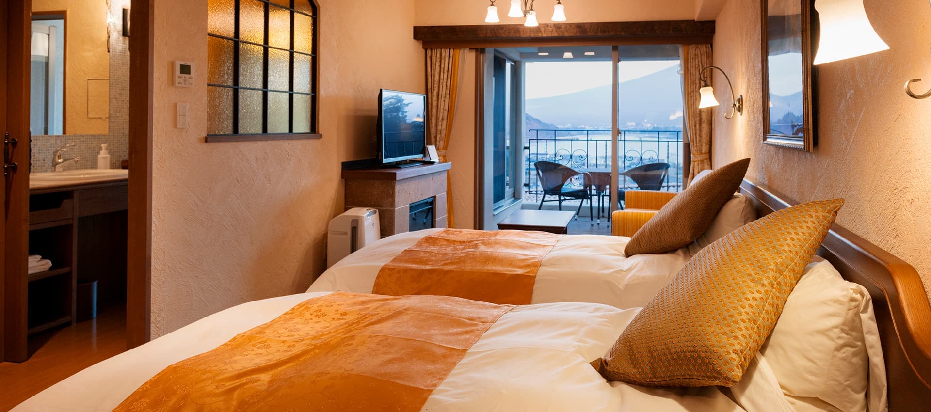 Guest room at La Vista Fuji Kawaguchiko with twin beds, warm plaster walls and a balcony opening to the lake view