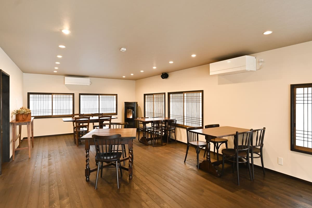 Dining hall with dark wood floor, antique wooden tables and chairs and latticed windows