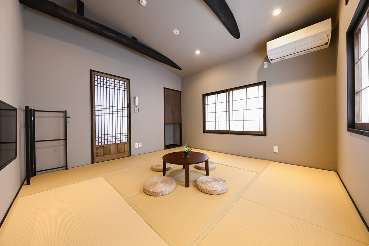 Spacious tatami room with exposed dark beam, latticed wooden door and round low table