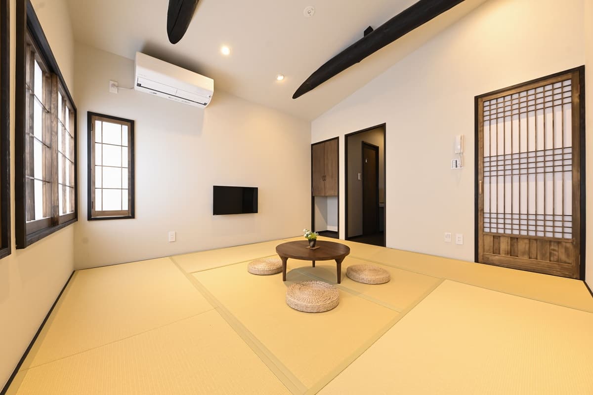 Tatami room with vaulted ceiling beam, wall-mounted TV and traditional latticed sliding door