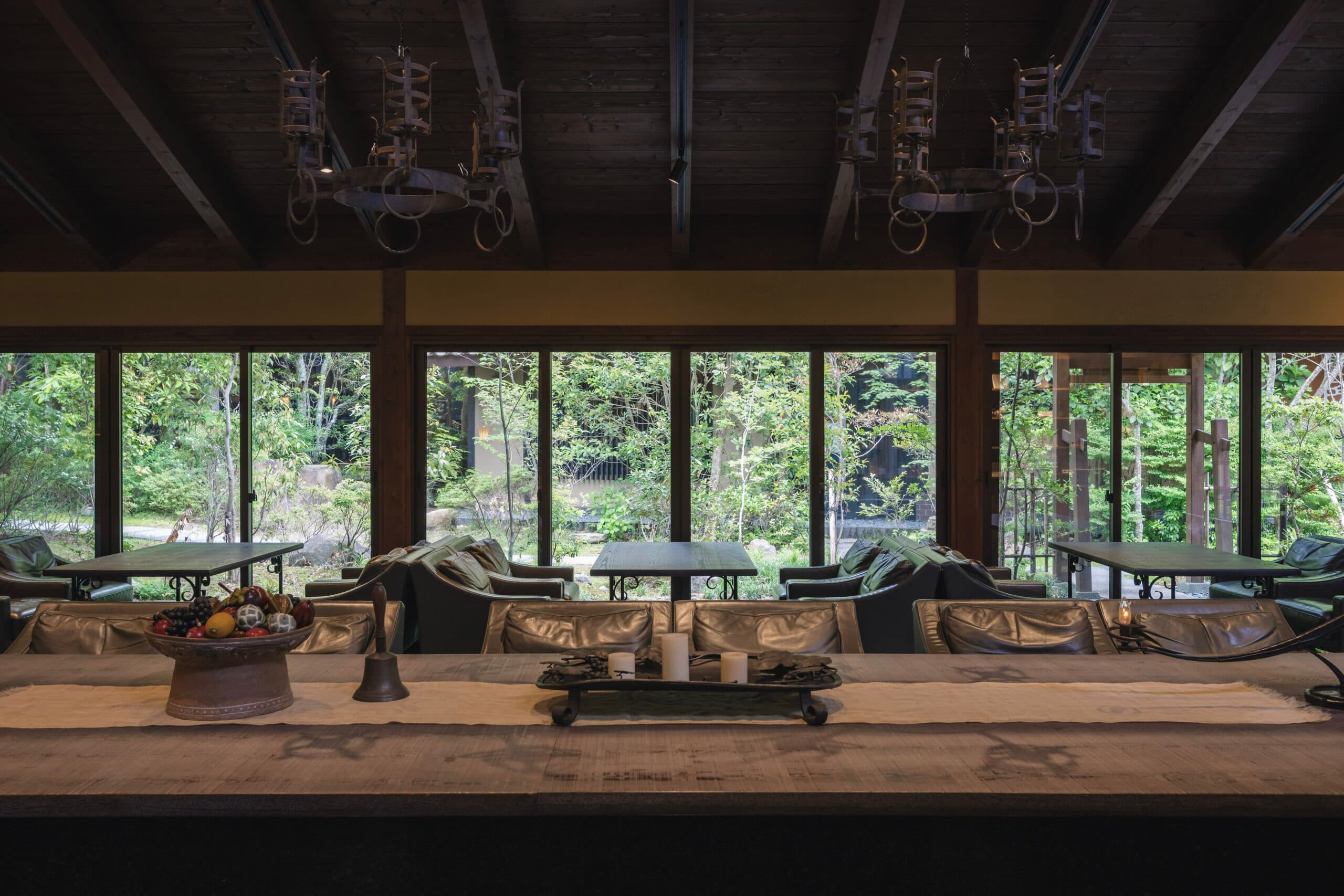 Tatami sitting room with low table facing tall forest-view windows in a Gosho Bessho villa