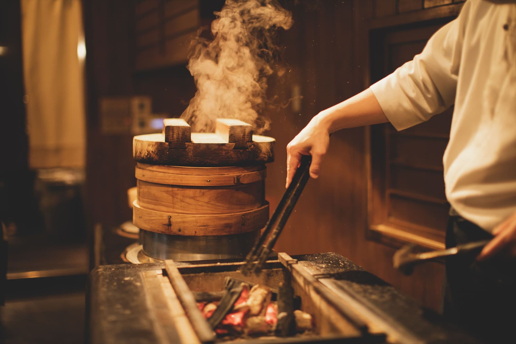 Warmly lit wooden dining counter with hanging pendant lamps at Hotel Hanakoyado, Arima Onsen