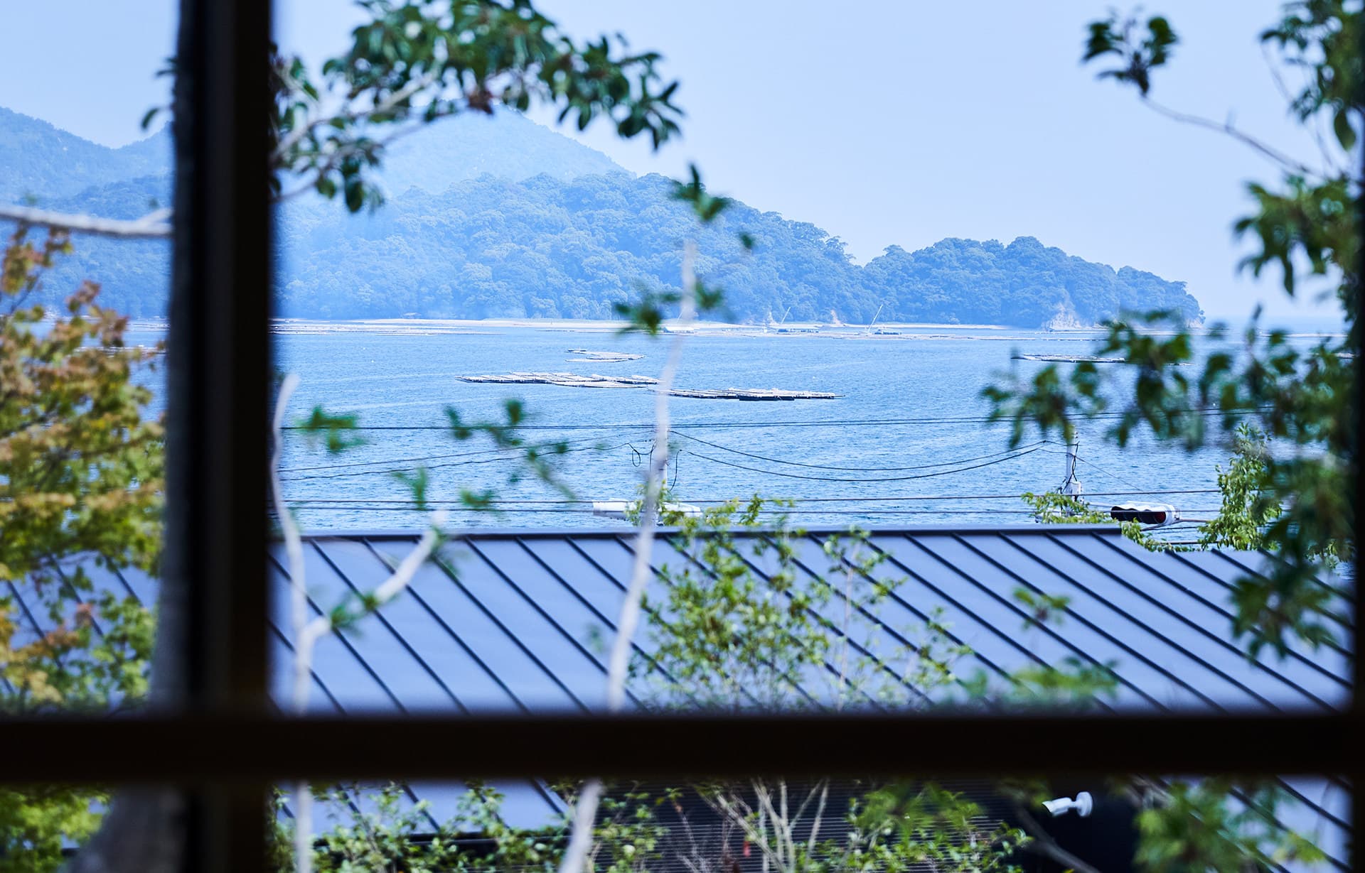 View of the Seto Inland Sea and the wooded hills near Miyajima seen through a guest room window at IBUKU