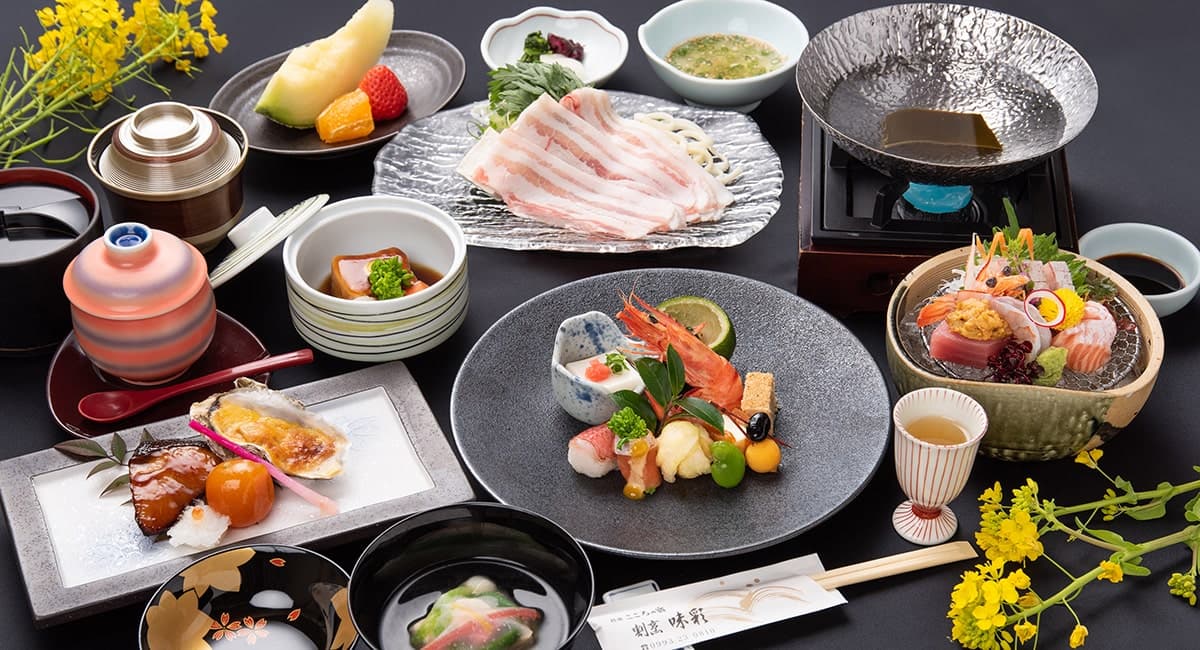 Kaiseki course meal featuring pork shabu-shabu, sashimi and seasonal appetizers laid out on a dark table