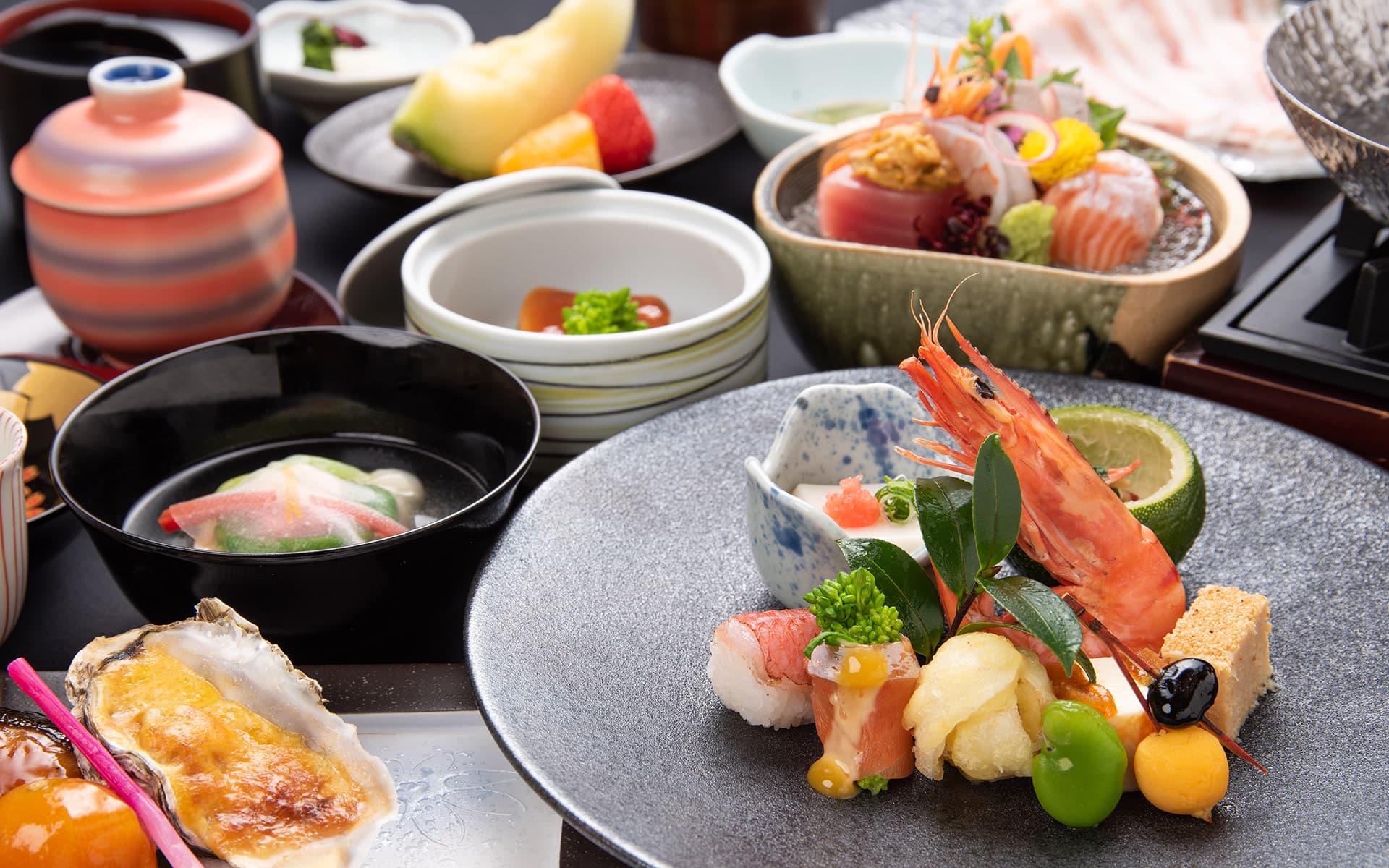 Kaiseki dinner spread with sashimi boat, grilled oyster and seasonal small dishes served at Ibusuki Kokoro no Yado