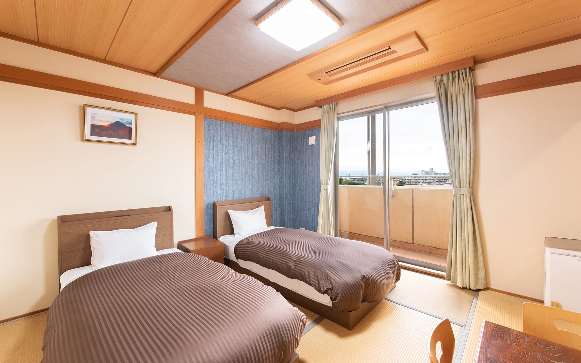 Twin-bed guest room on tatami flooring with a private balcony overlooking the Ibusuki townscape