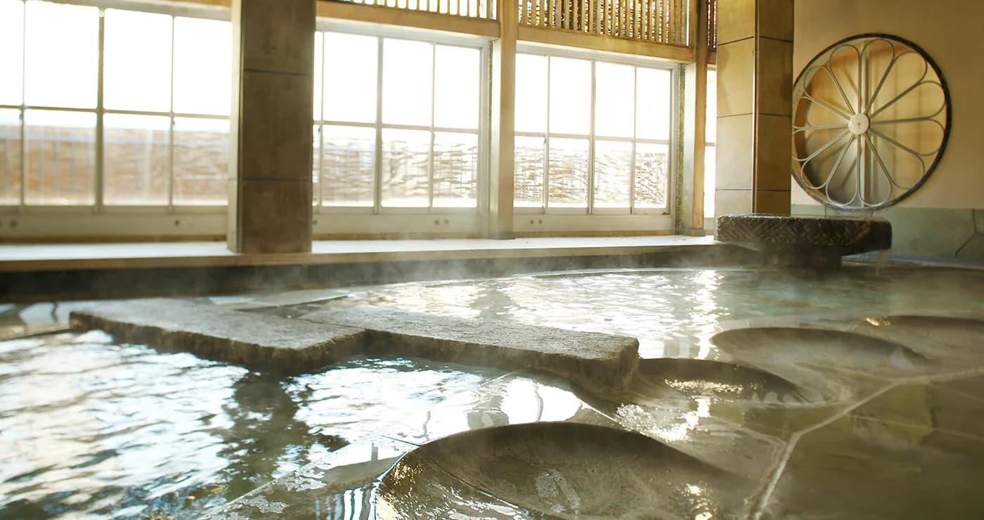 Large indoor stone hot spring bath with bright window wall at Yu-Kairo Kikuya, Izu