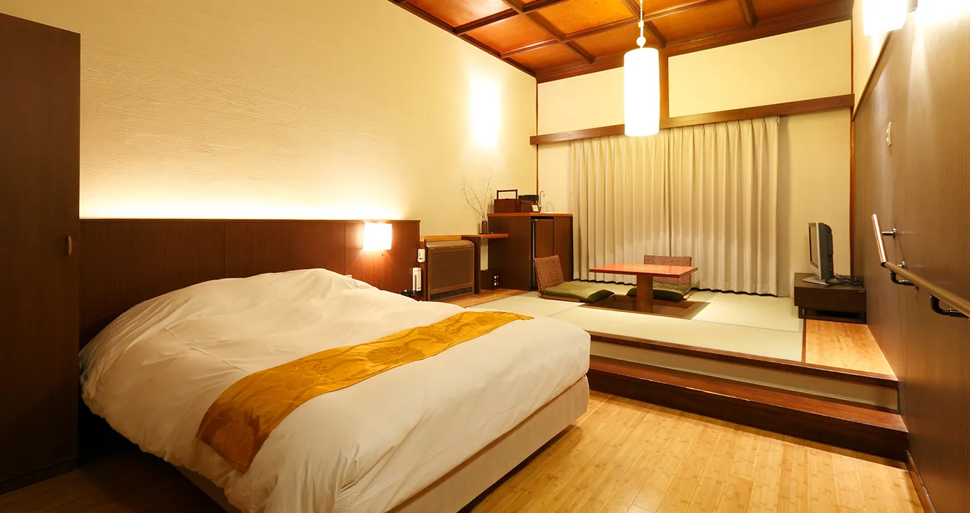 Modern Japanese-style room with low bed and raised tatami alcove at Yu-Kairo Kikuya, Shuzenji