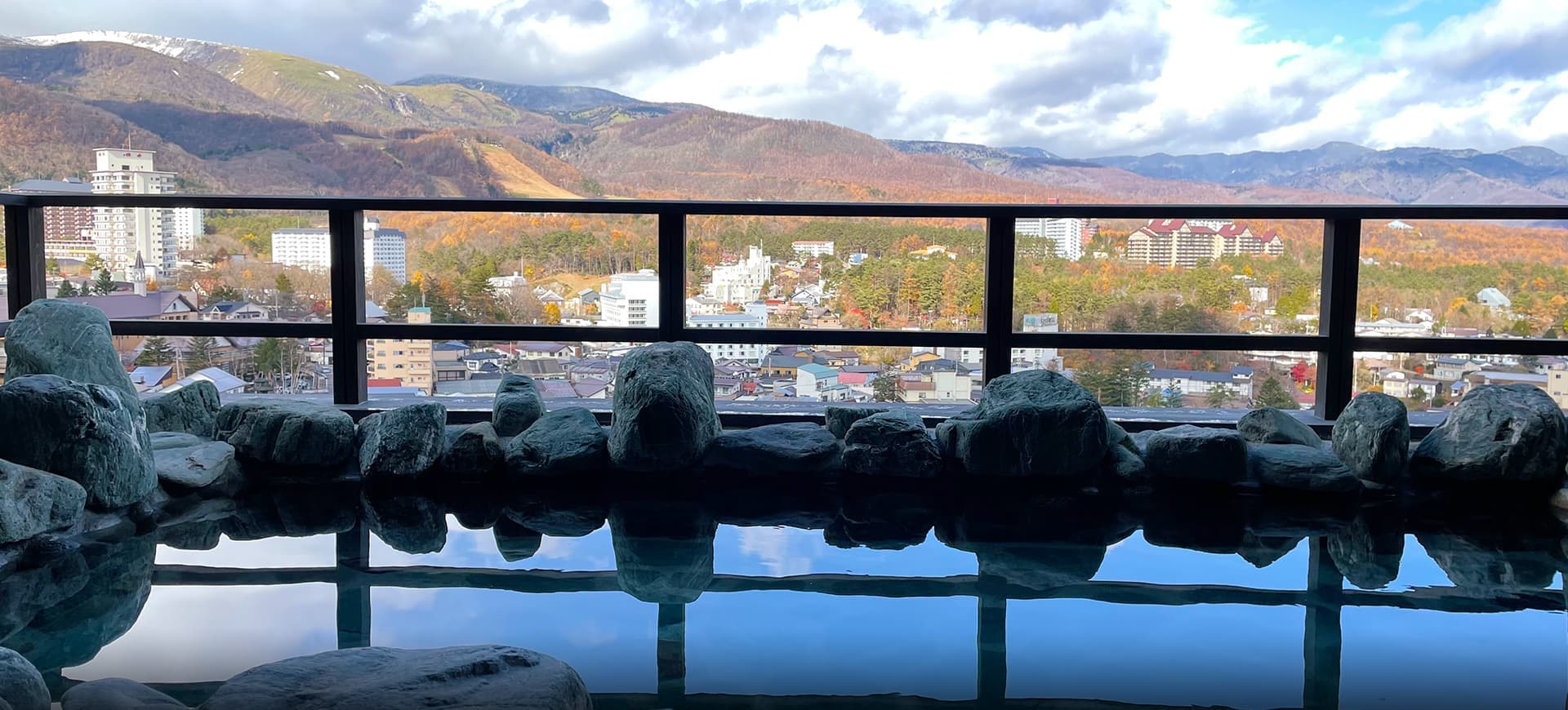 Rooftop open-air rock bath at La Vista Kusatsu Hills overlooking Kusatsu town and autumn-coloured mountains