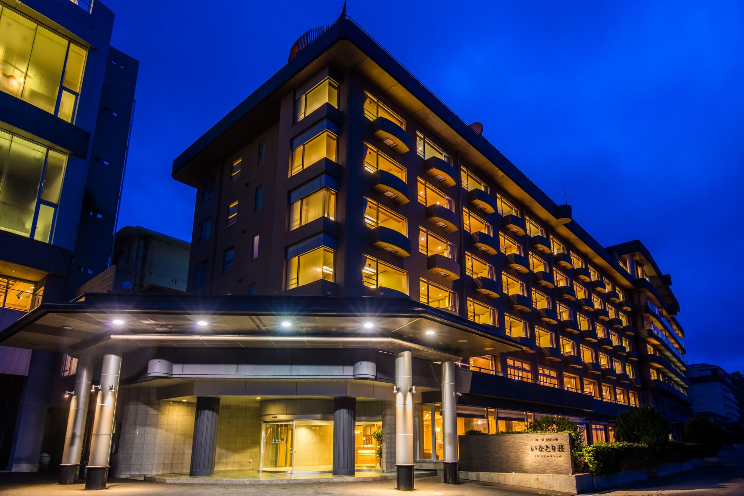 Inatoriso ryokan exterior illuminated at dusk in Inatori Onsen, Izu, overlooking the sea