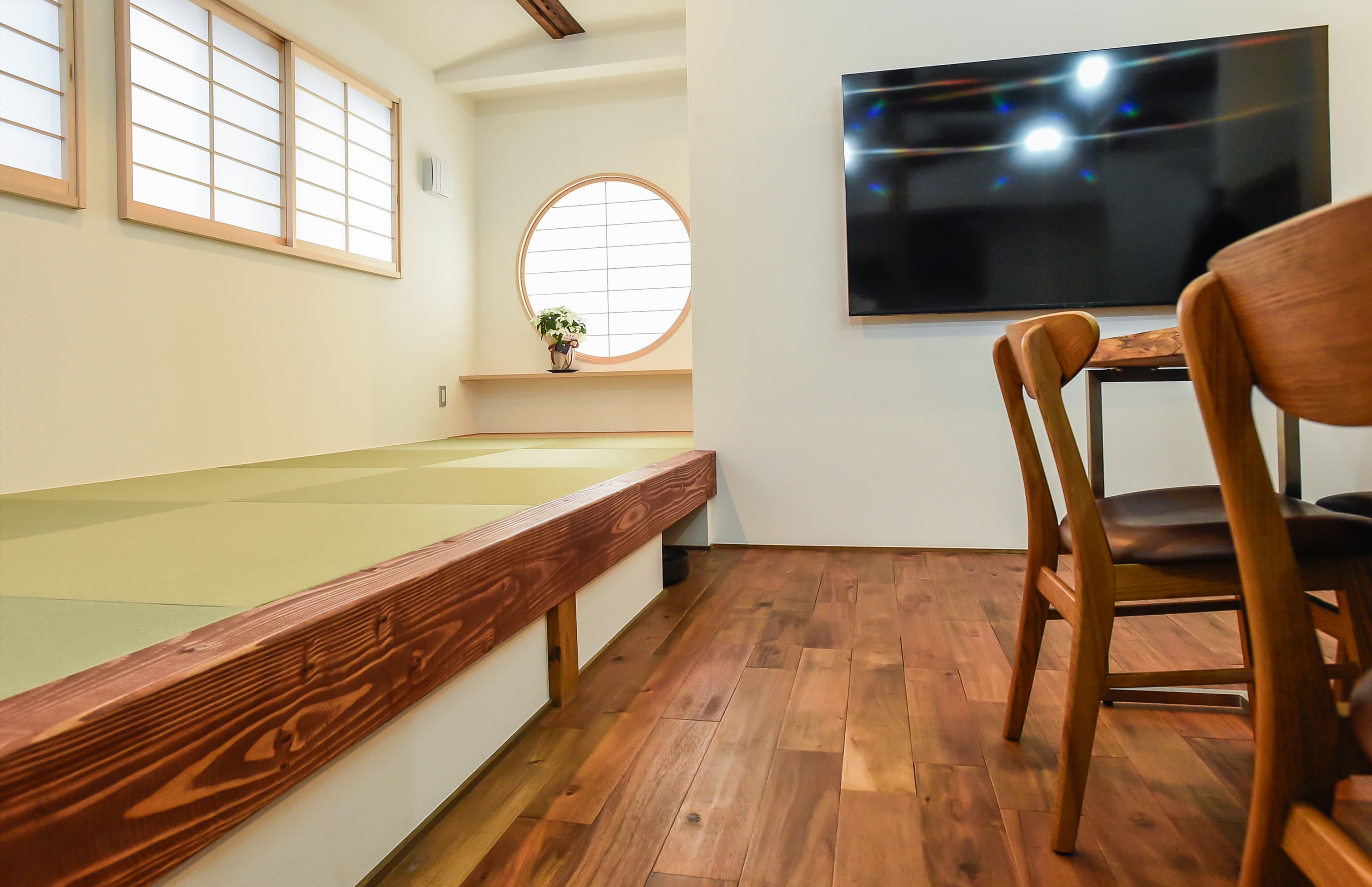 Modern room at Ito Ryokan Tokyo with raised tatami platform, round shoji window and wood floor