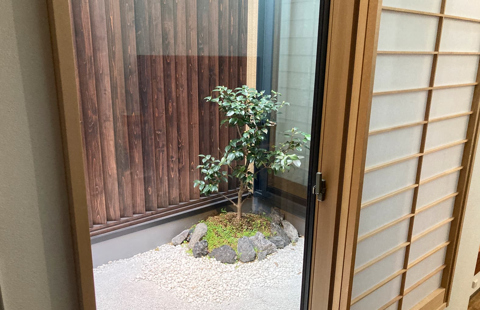 Interior courtyard tsubo-niwa garden at Ito Ryokan Tokyo viewed through a shoji doorway