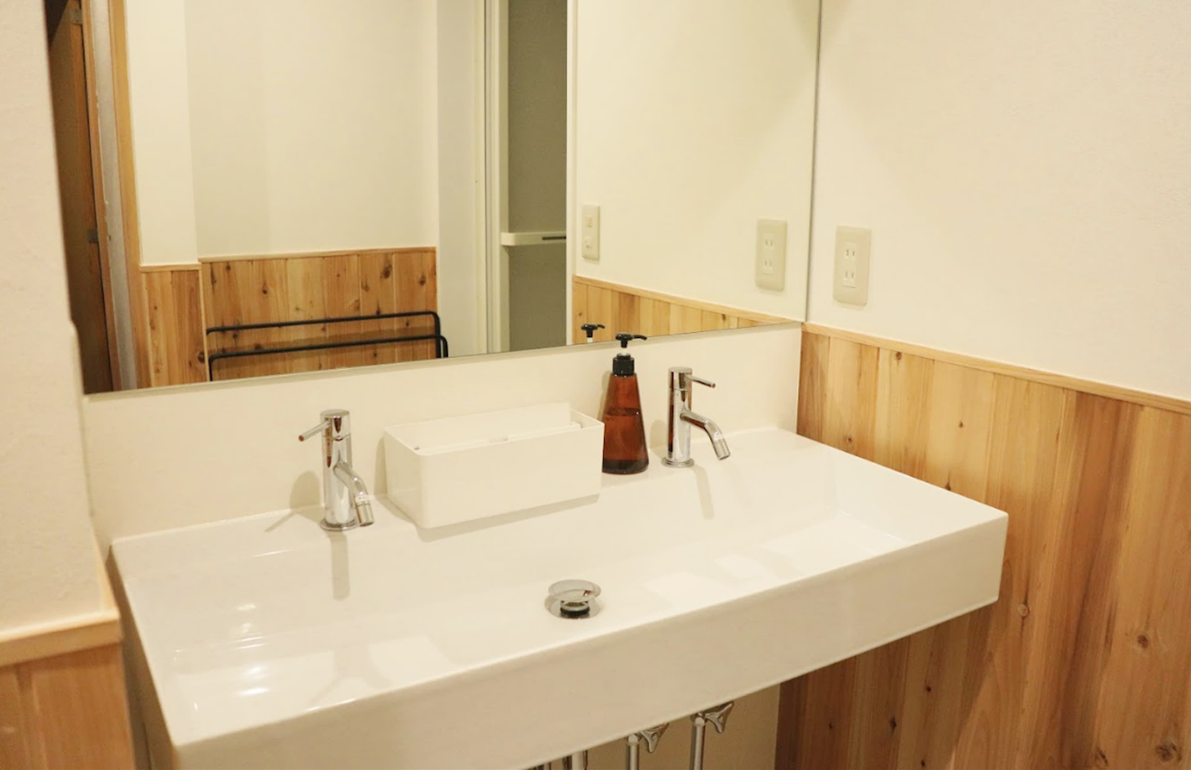 Washbasin vanity area at Ito Ryokan Tokyo with cedar wood paneling and wide mirror