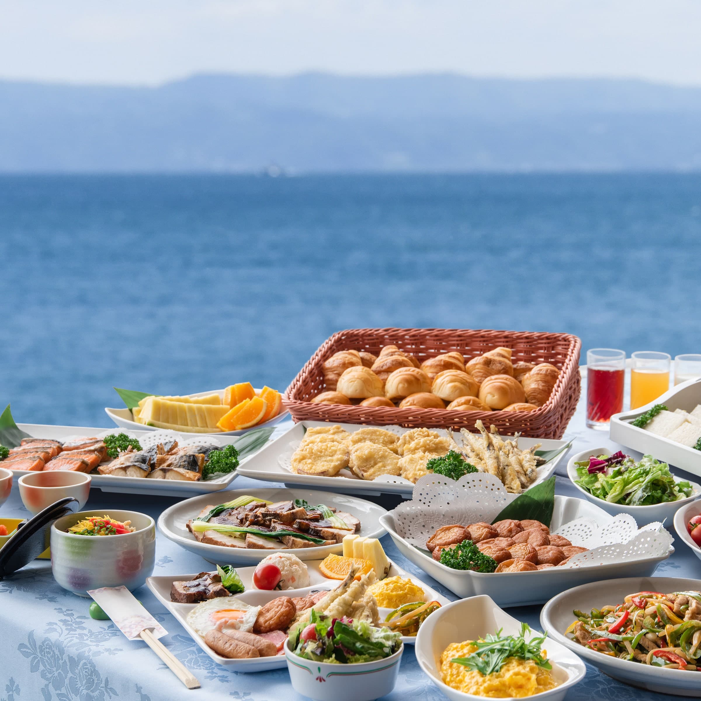 Seaside breakfast and buffet spread of dishes, breads and fruit set against the ocean at Ibusuki Kaijo Hotel