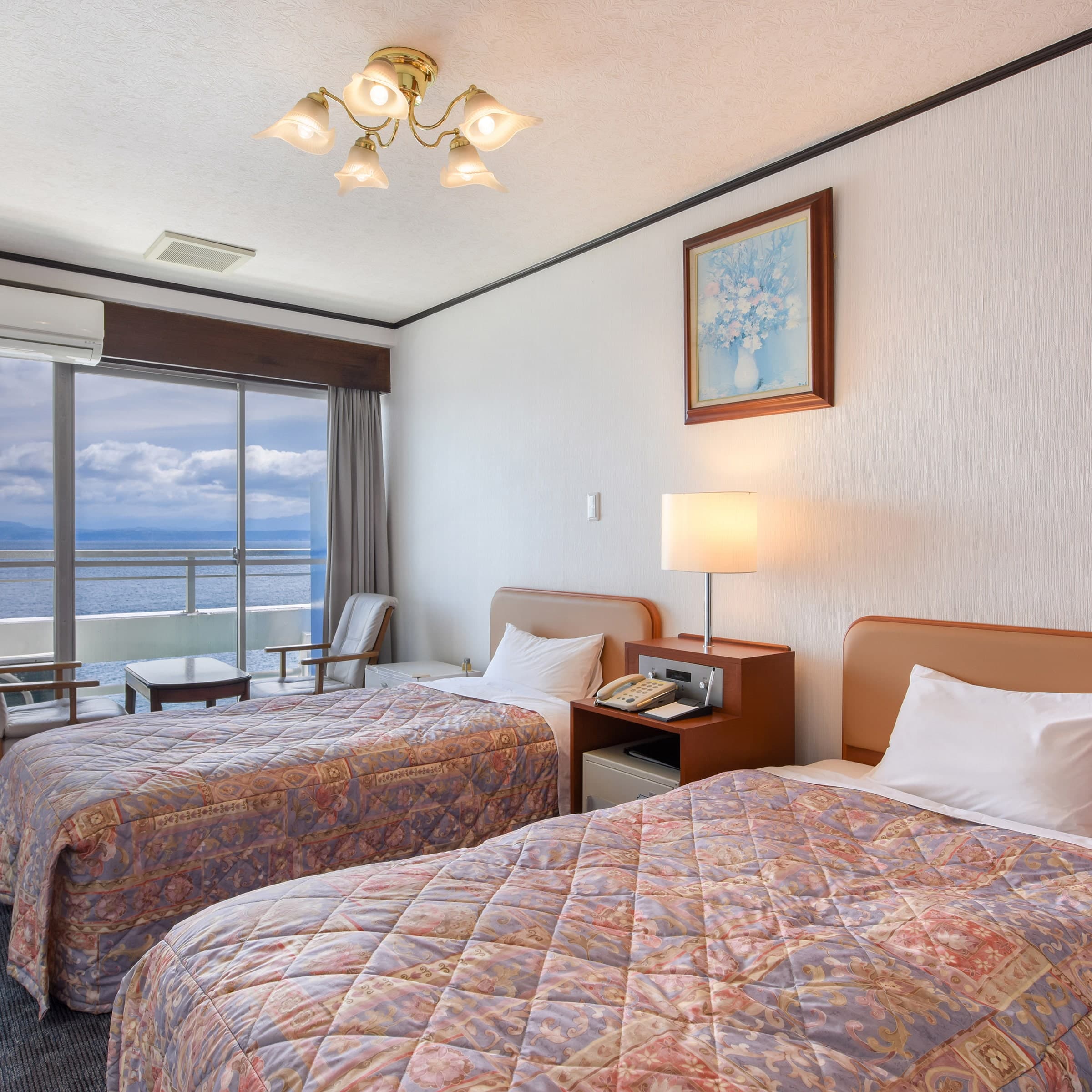 Western-style twin guest room with two beds and a private balcony facing the sea at Ibusuki Kaijo Hotel