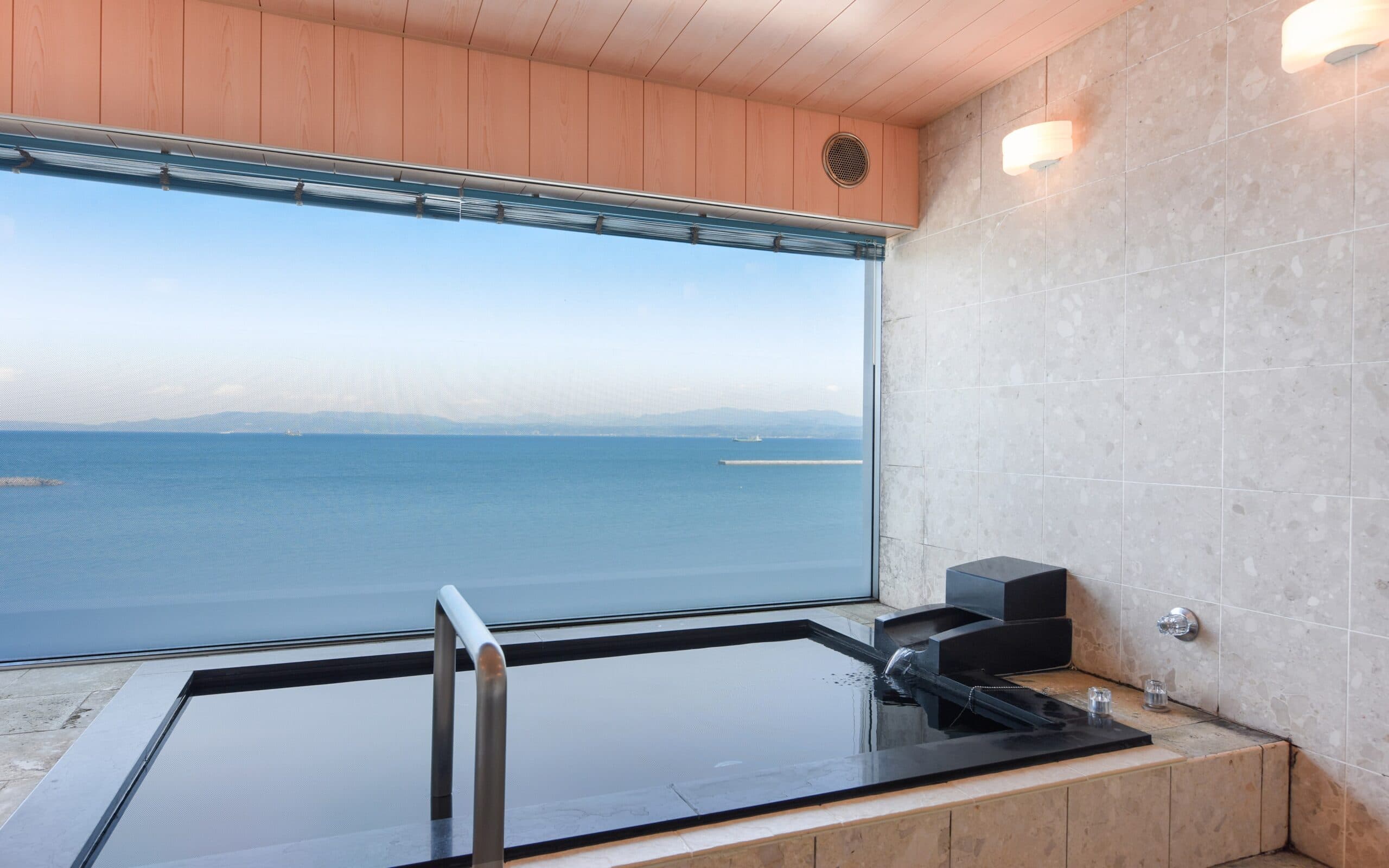 Private stone ocean-view bath with a large picture window overlooking Kinko Bay at Ibusuki Kaijo Hotel