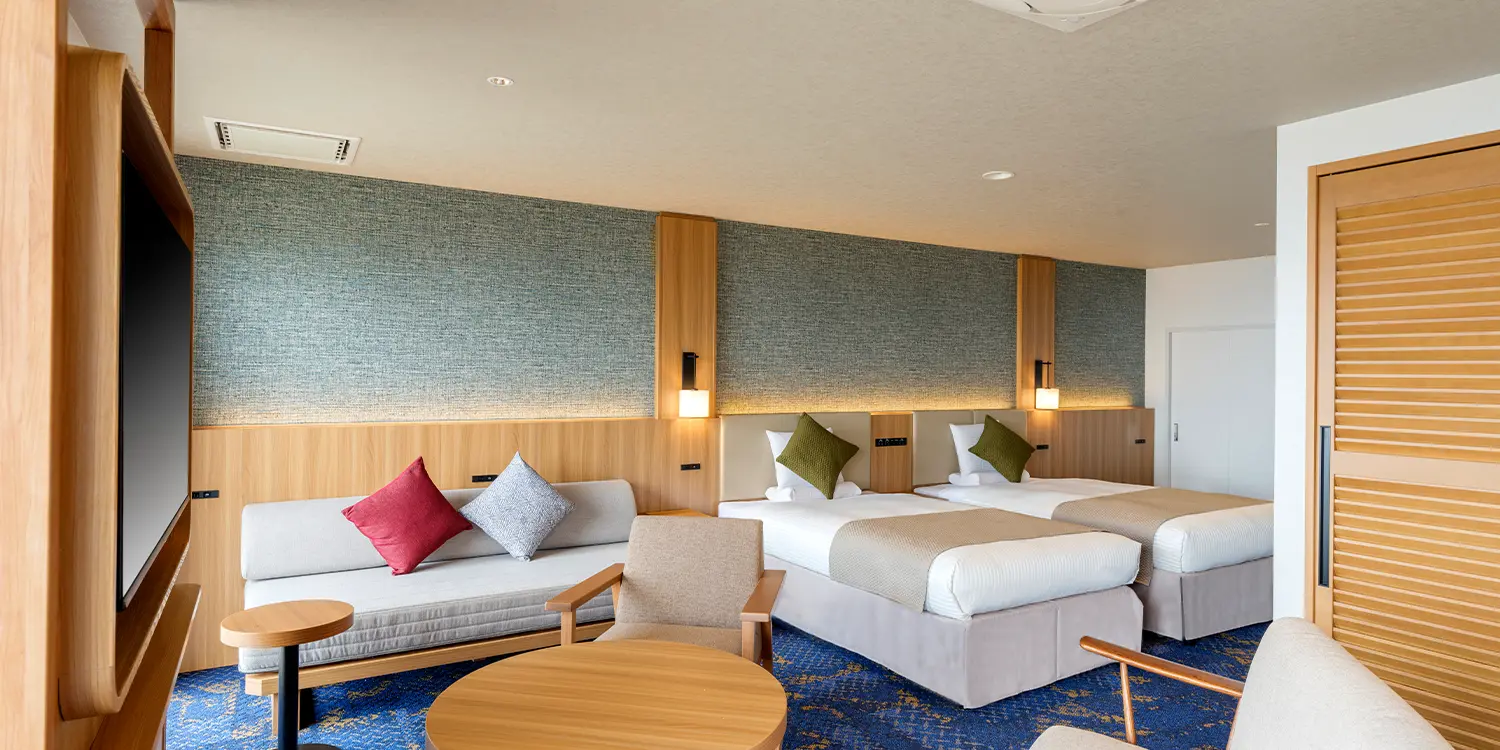 Modern guest room at Kamenoi Hotel Atami with twin beds, wood paneling and a sofa lounge corner