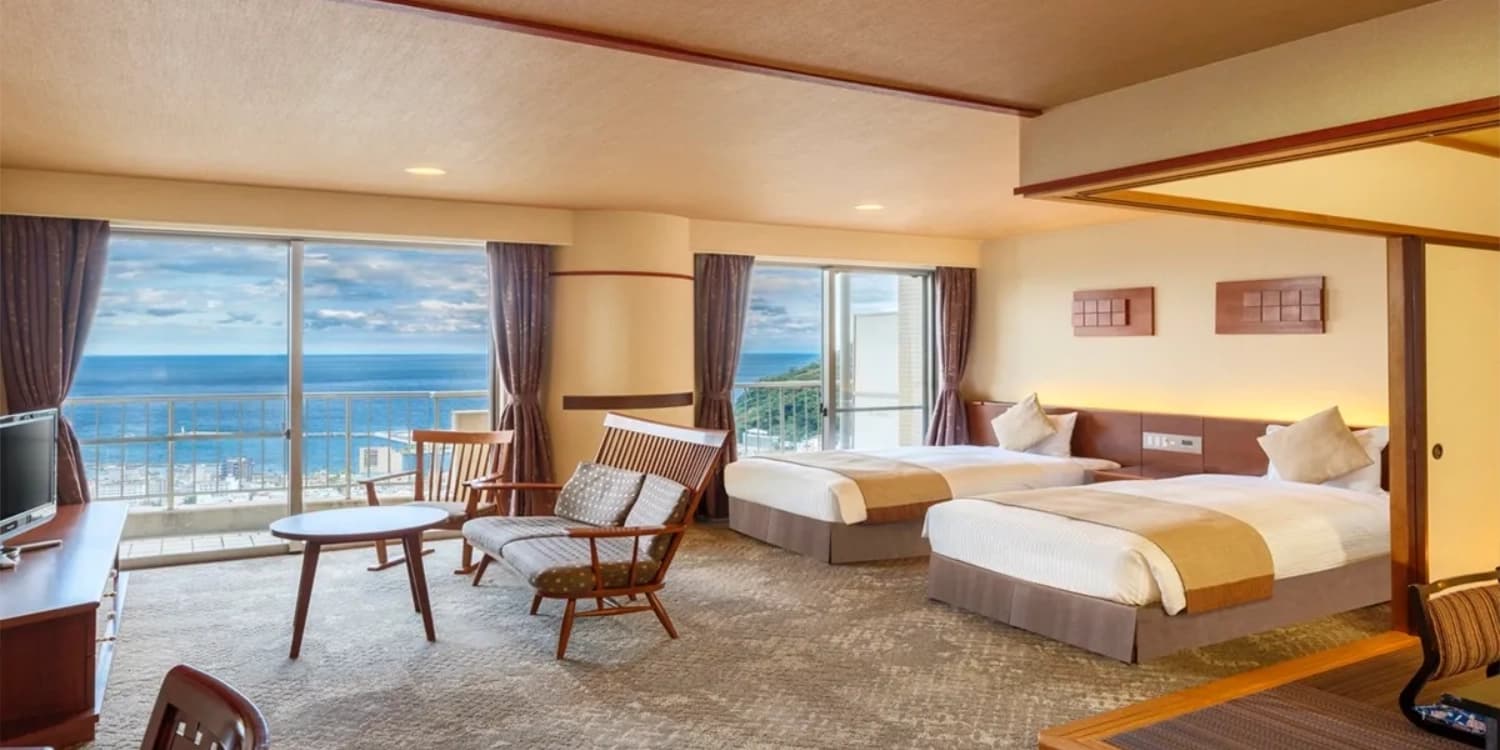 Spacious ocean-view guest room at Kamenoi Hotel Atami with twin beds facing windows over Sagami Bay