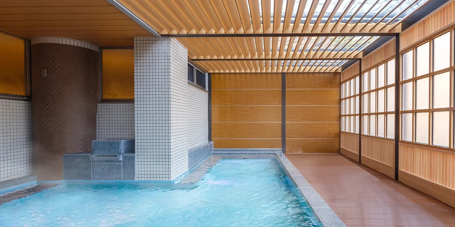 Indoor hot-spring bath at Kamenoi Hotel Atami framed by warm wooden lattice and shoji screens