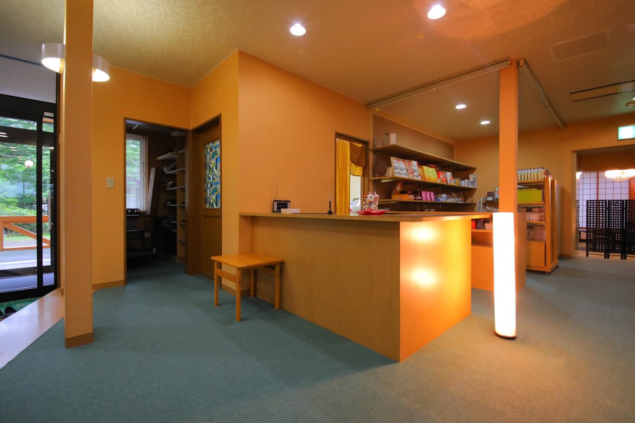 Lobby and reception area with warm wood counter and forest view at Mori no Yu Sanseikan, Karurusu Onsen